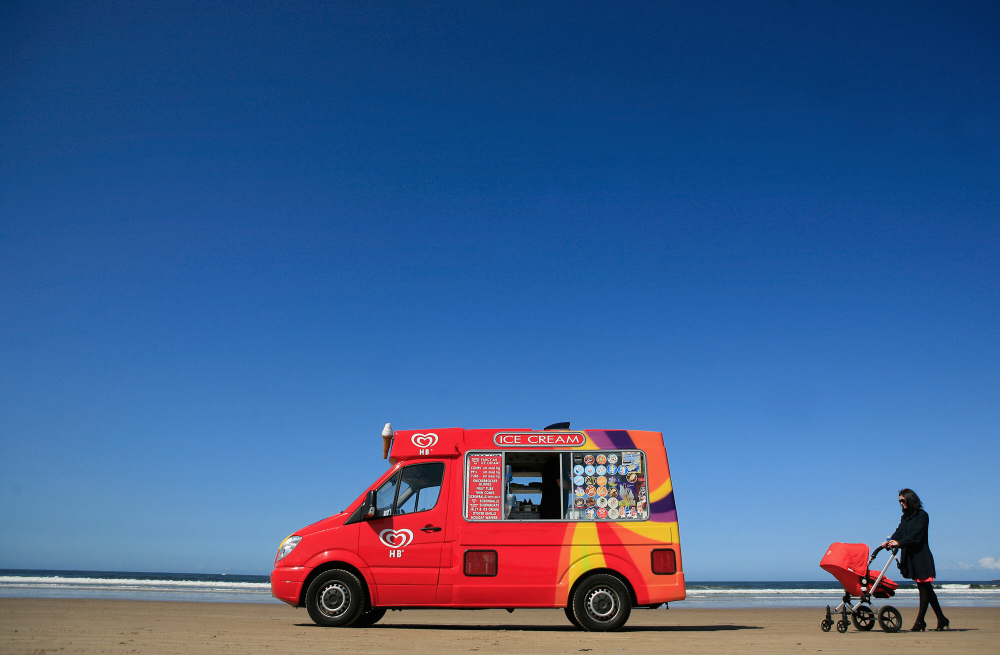 A woman pushes her pram towards an ice cream vendor on Portstewart Strand beach, 2009.