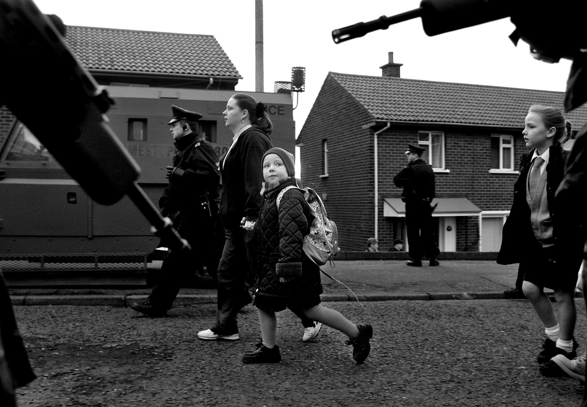 Children walk to school under armed guard during the Holy Cross dispute in Belfast, 2001.