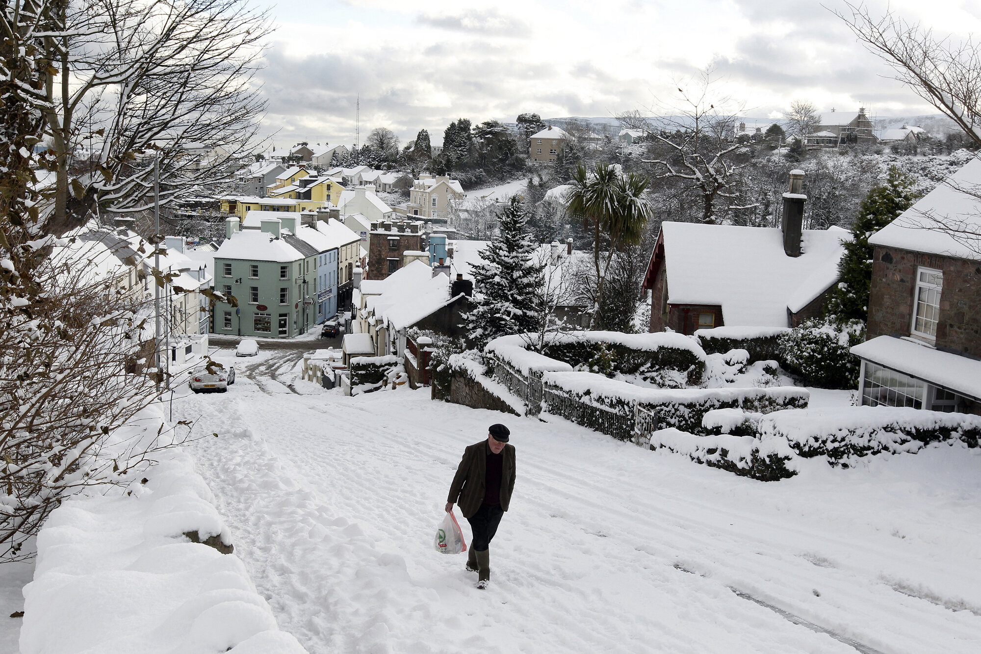 A man makes his way home with his shopping through heavy snow in the village of Cushendall , 2010.