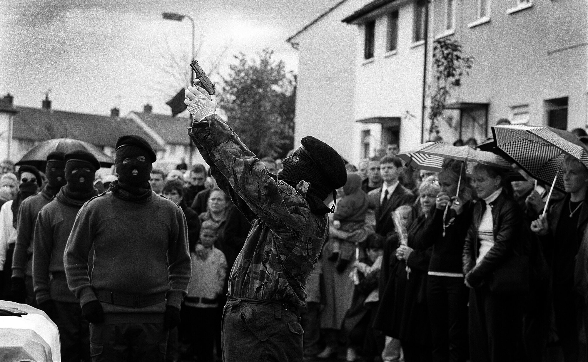 An member of a INLA colour party shoots a volley of shots over the coffin of a murdered colleague in West Belfast. 2001.