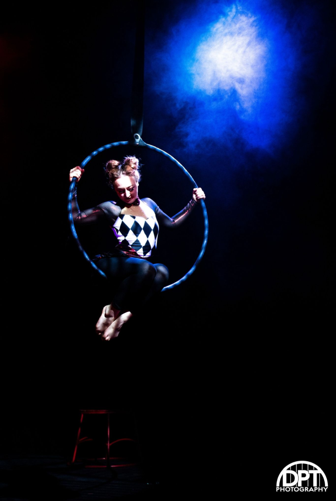 emma performing aerial hoop in a clown outfit