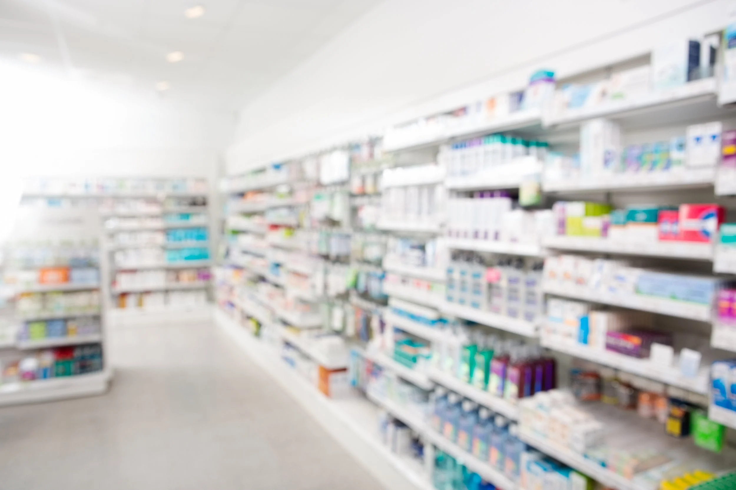 Blurred view of pharmacy shelves stocked with medicines and healthcare products.
