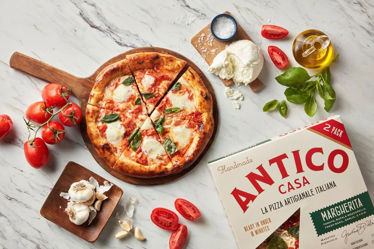 Antico Casa pizza and ingredients on a marble surface