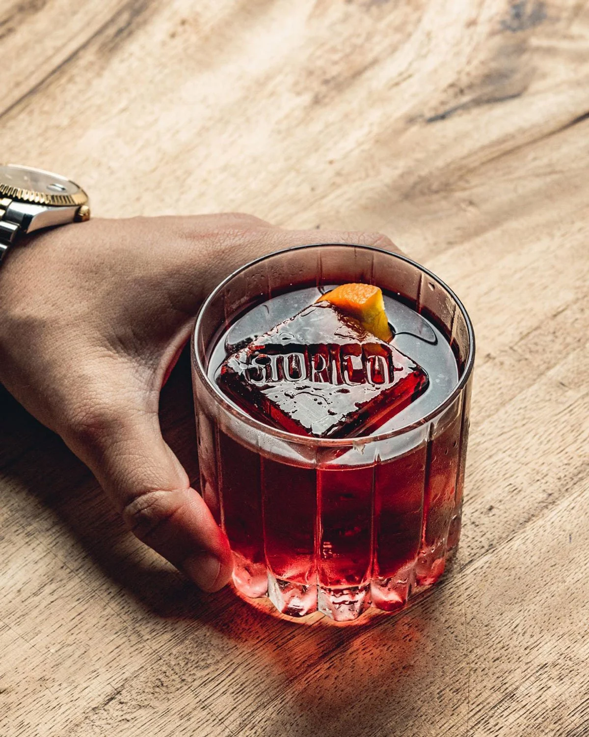 A hand holding a negroni from Storico Vino