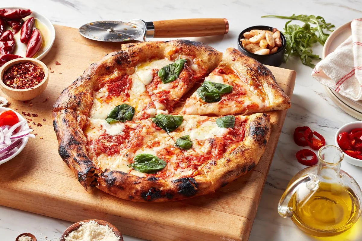 Antico Casa pizza on a cutting board with ingredients around it