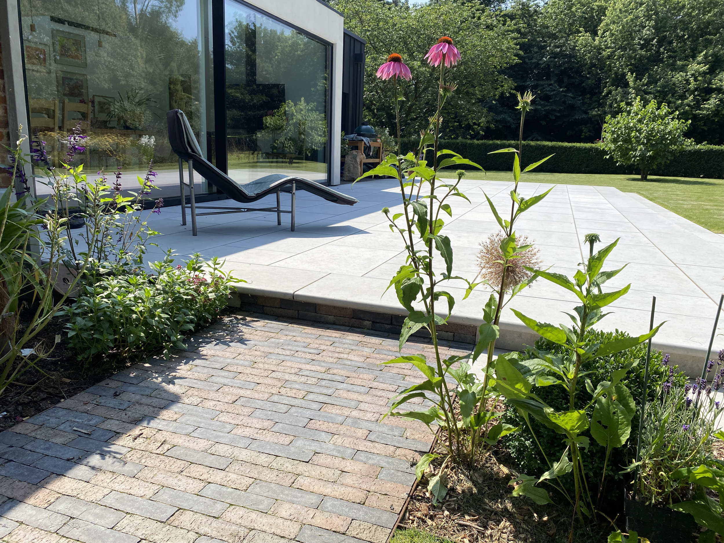 Clay paver paths connect to Jura Limestone terrace. Buxus, Allium and Echinacea border the terrace.