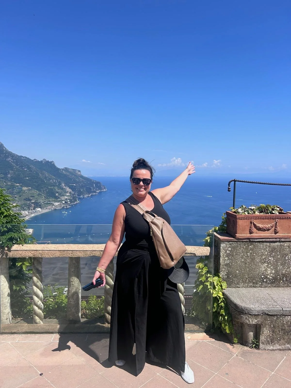 A woman traveling solo posing along the Amalfi, Italy coastline