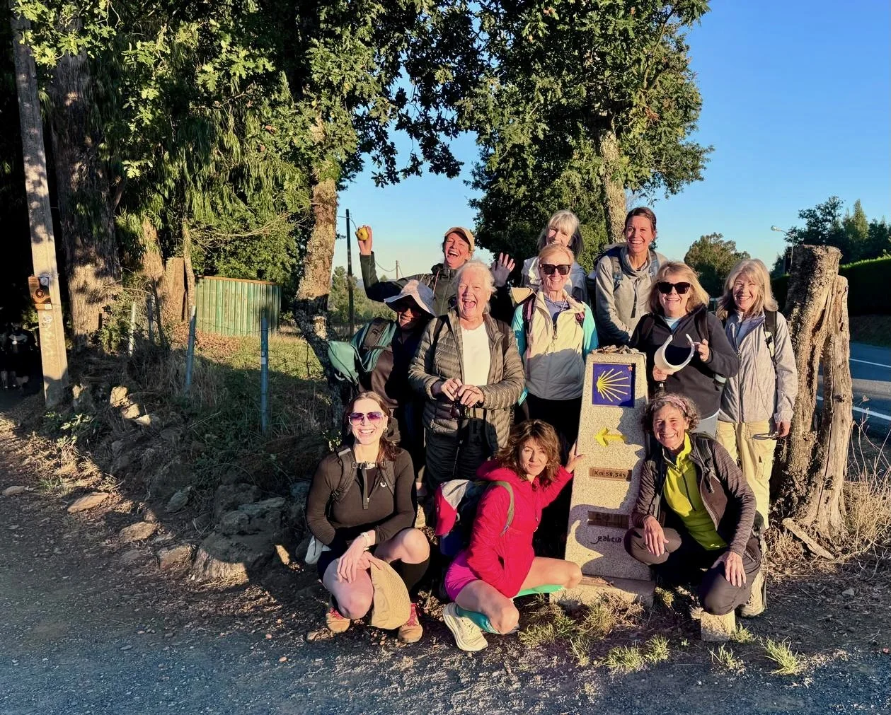 Group of women travelers standing next to Camino de Santiago trail marker