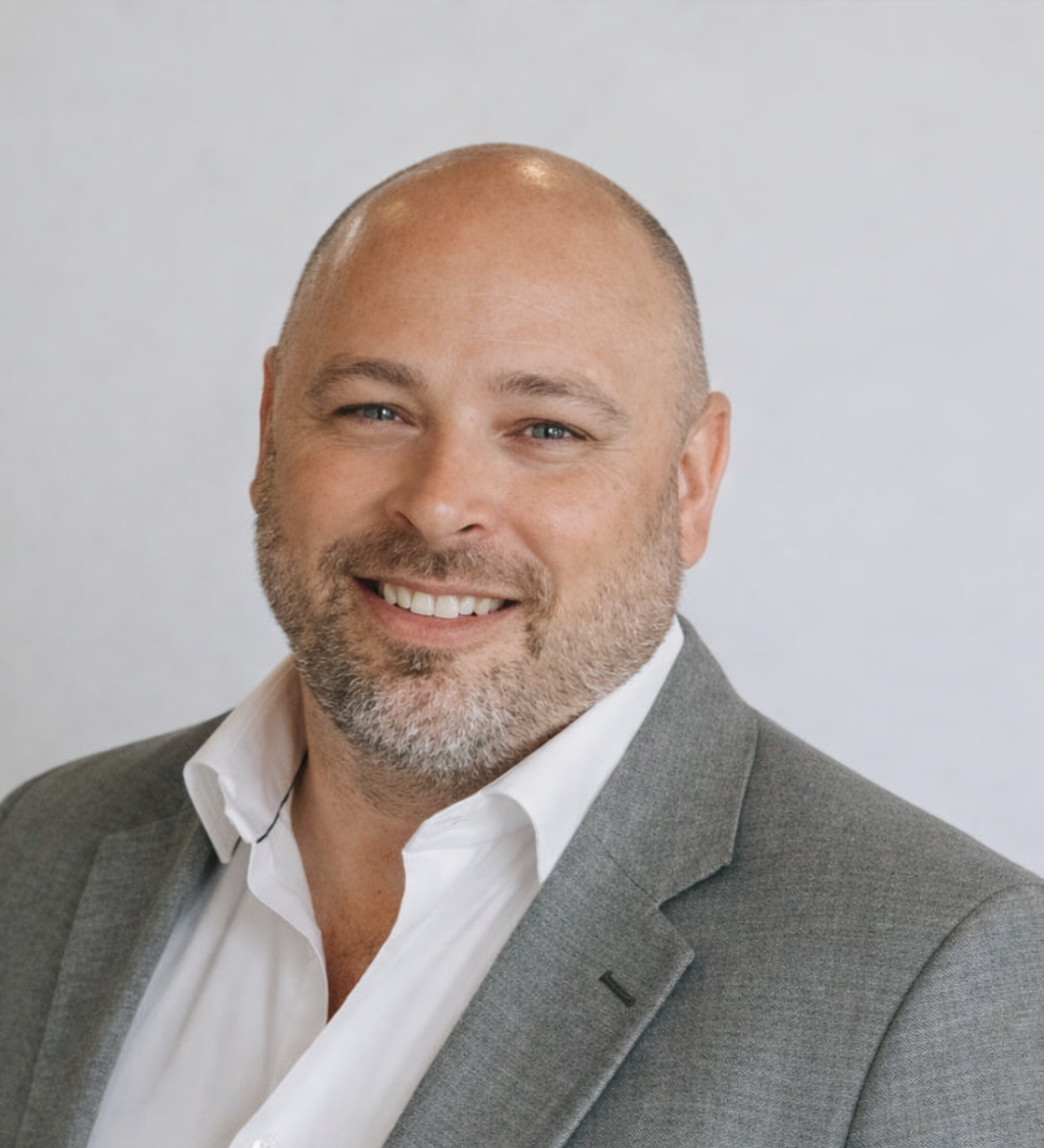 Luke O’Hare, Chief Executive Officer of JAK’s, professional headshot in-store wearing a grey blazer and white shirt.
