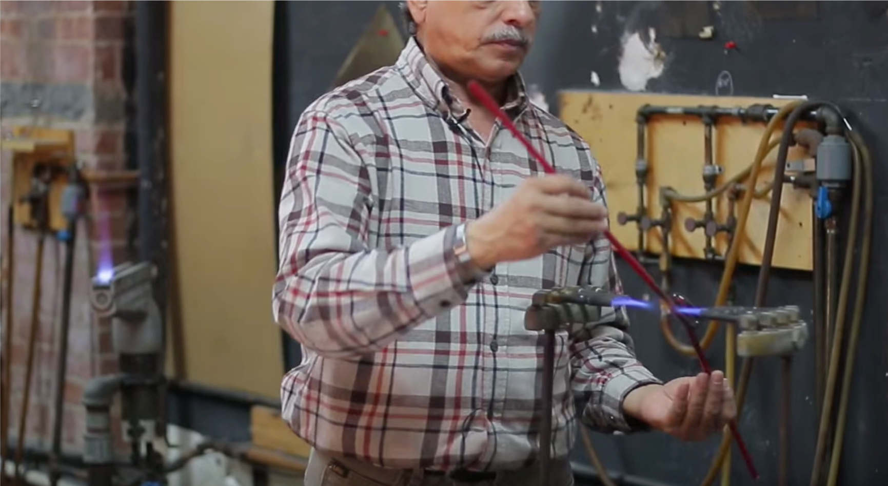 Neon glass fabricator using a torch to bend the glass tube. Video Still: The Past, Present and Future of Neon in New York w/ Let There Be Neon (15:03-15:14)
