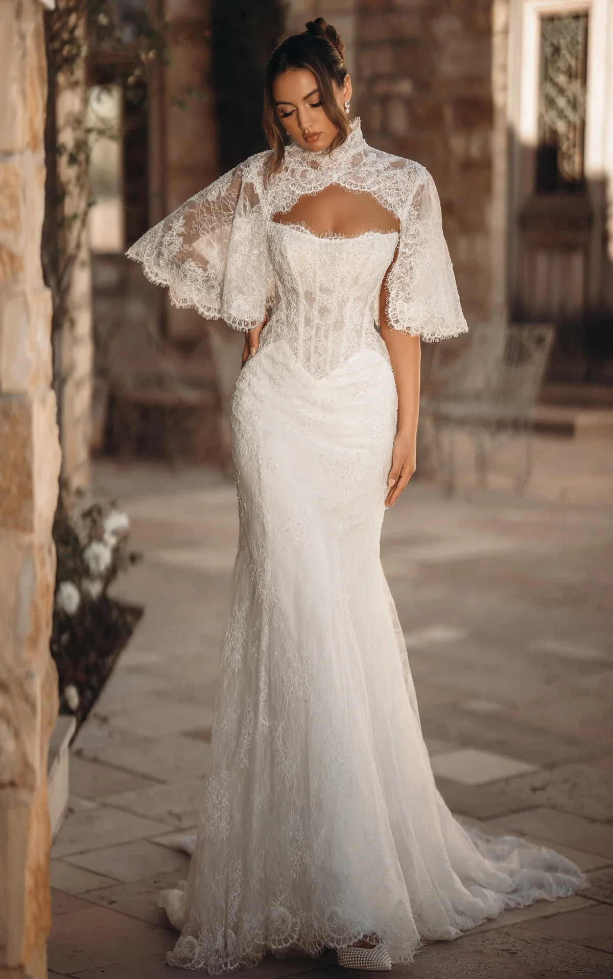 Ivory lace mermaid wedding dress with a corset bodice and high-neck lace cape by Martina Liana