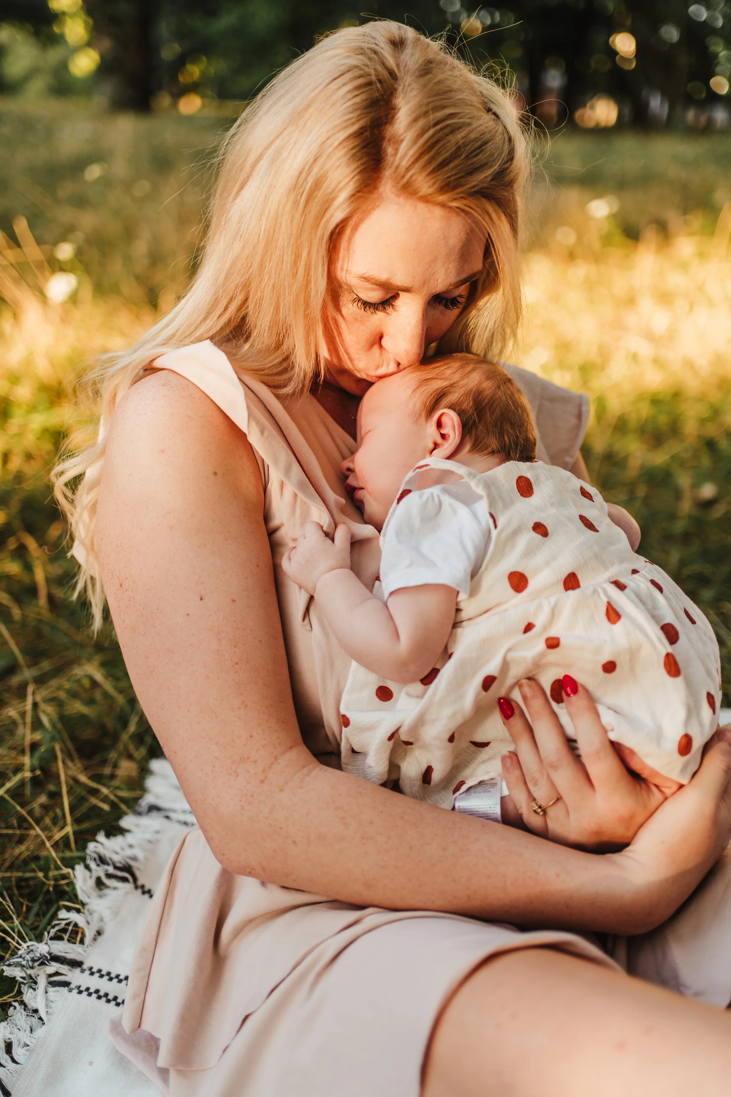 mama przytula malutką córeczkę, sesja noworodkowa  o zachodzie słońca w parku