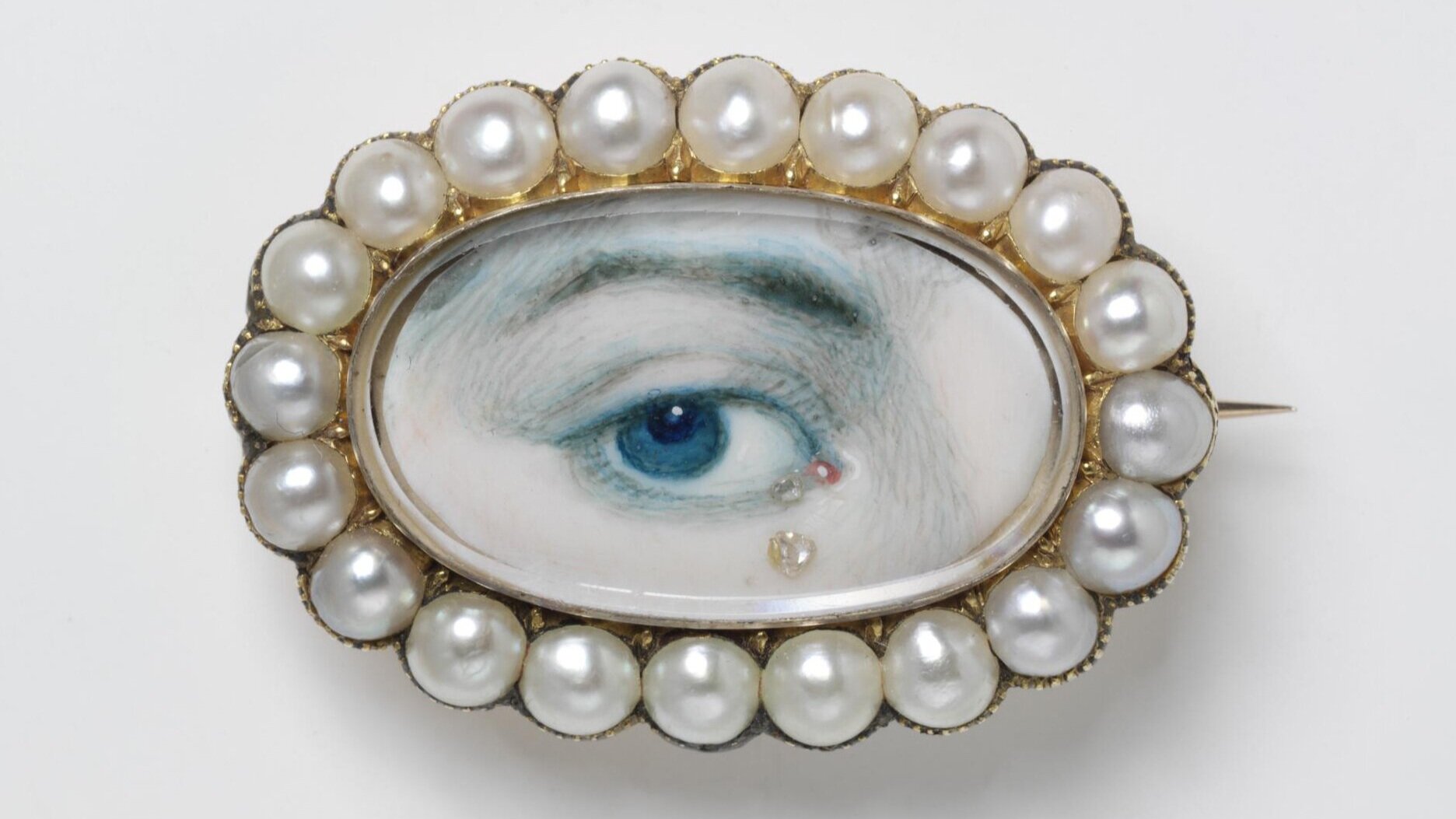 What is a Lover’s Eye? Today we may send a selfie to our partner, but between the 1780s and 1820s, a Lover’s Eye jewel was a secret way in which romantic relationships communicated. A painted miniature portrait of a person’s eye, these tiny pieces were only centimeters in size and were exchanged between pining lovers. Due to their small stature, Lover’s Eye jewellery could be both secretly or overtly worn, with the former for unknown courtships and the latter for public displays of affection. The painted portrait was often crowned with gems and displayed in ovals, crescent moons or floral-like clusters to emphasise their inherent romantic nature. In many ways, these jewels were a literal jeweller’s version of a synecdoche, with the eye communicating the whole being’s intimate love and devotion. This one eye is the lustful watching gaze of their beloved, a “look” that can only be understood between romantic partners. In fact, eagle-eyed (pardon the pun) viewers may have noticed that this particular style of jewellery was actually shown in Bridgerton! Marina Thompson, the distant cousin of the Featherington family, is shown wearing a Lover’s Eye pendant in her opening scenes, an instant sign that she has promised her heart to another suitor. 