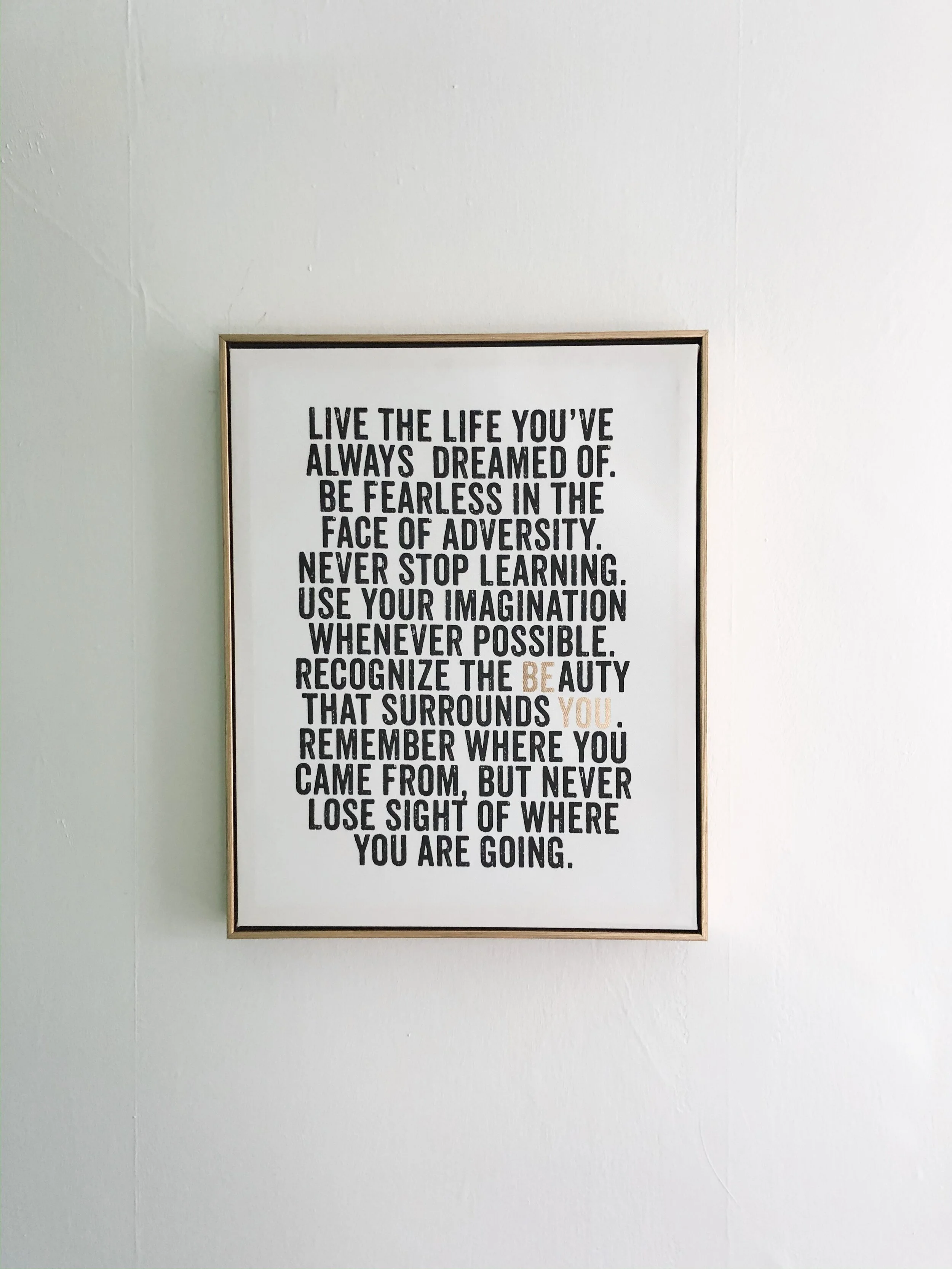 Framed quote on wall with motivational text about living life boldly and appreciating surroundings.