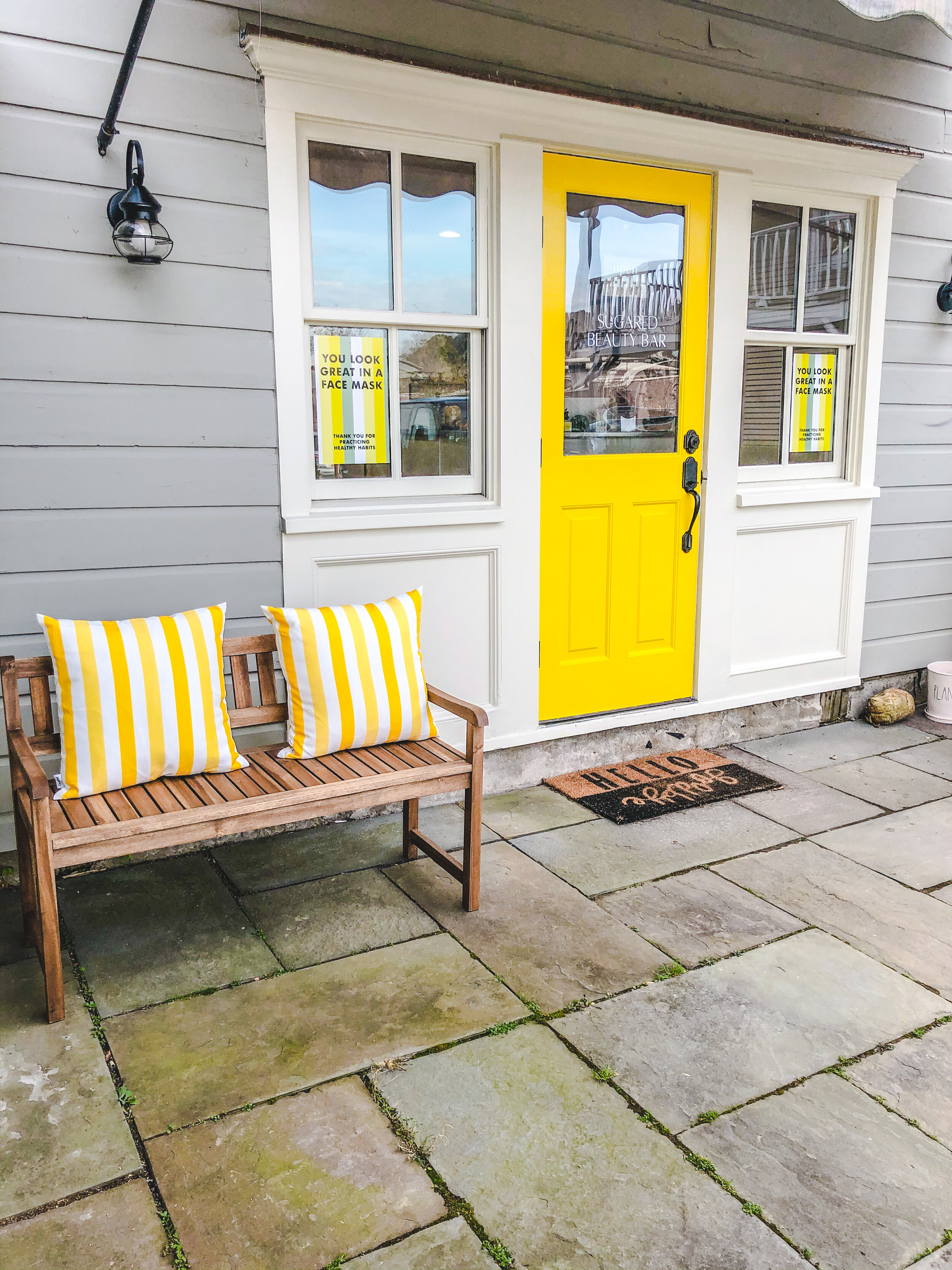 Colorful entrance with yellow door and striped pillows on a bench.