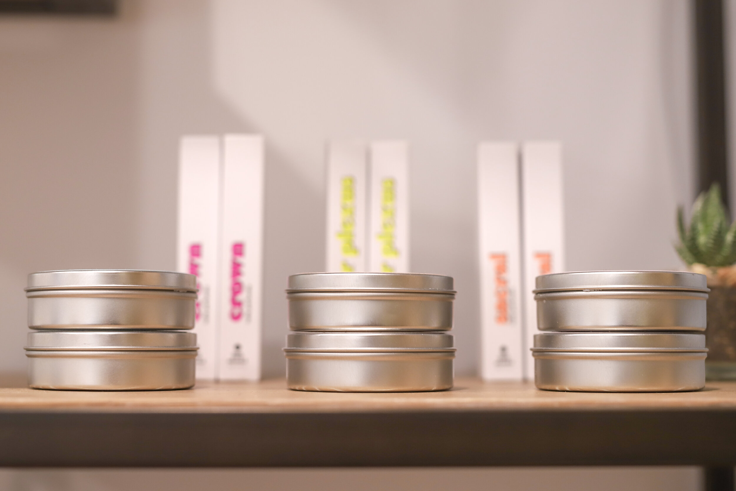 Stacked silver tins on a wooden shelf with books in the background.