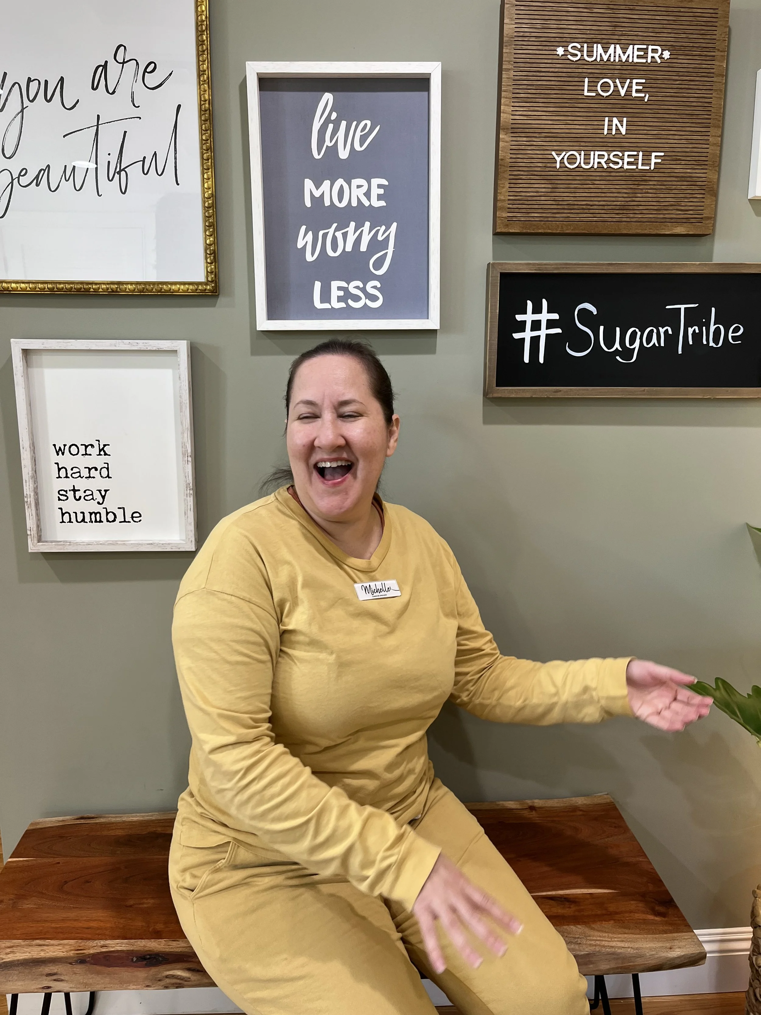 Smiling person with glasses and curly hair wearing a striped shirt.