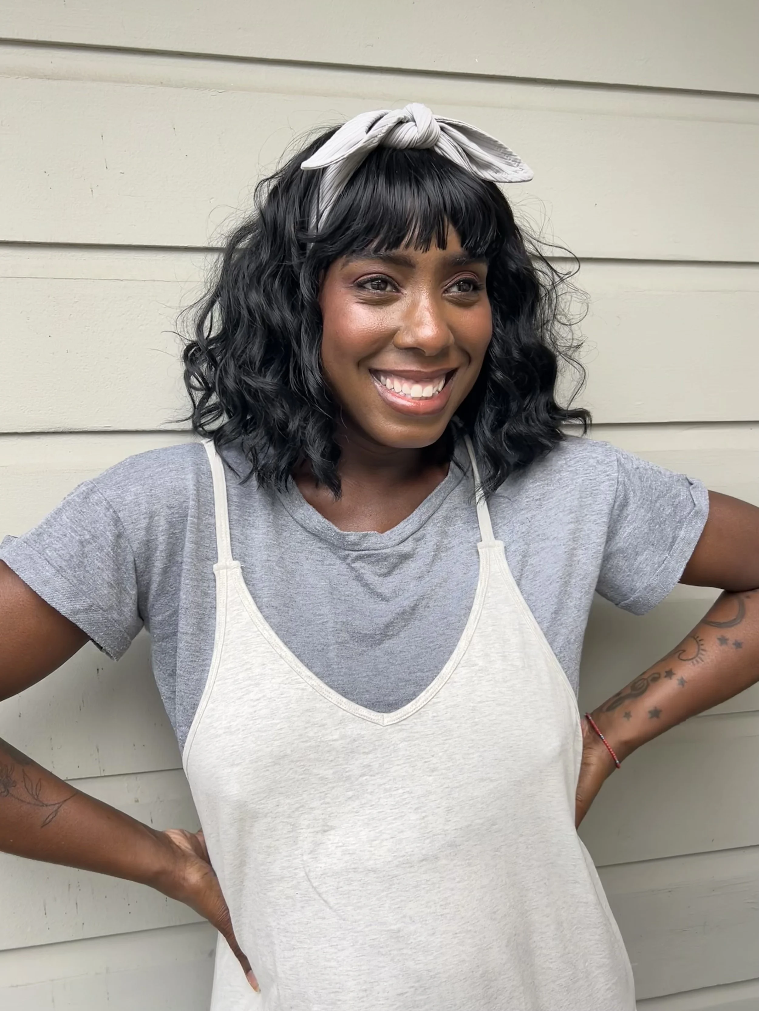 Smiling woman in a blue blouse with green foliage background.