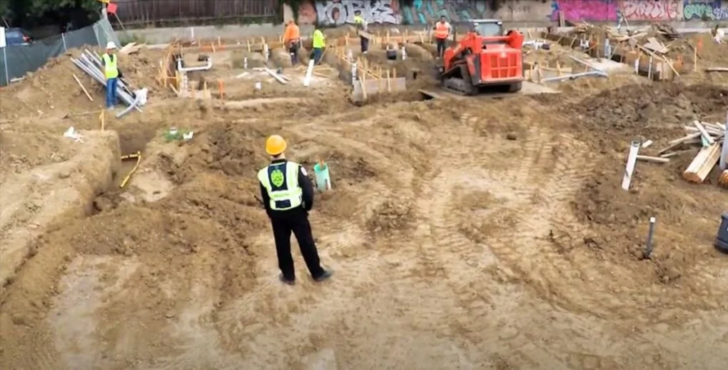 Security guard managing entry and exit of workers and vehicles at a construction site access gate in Ontario