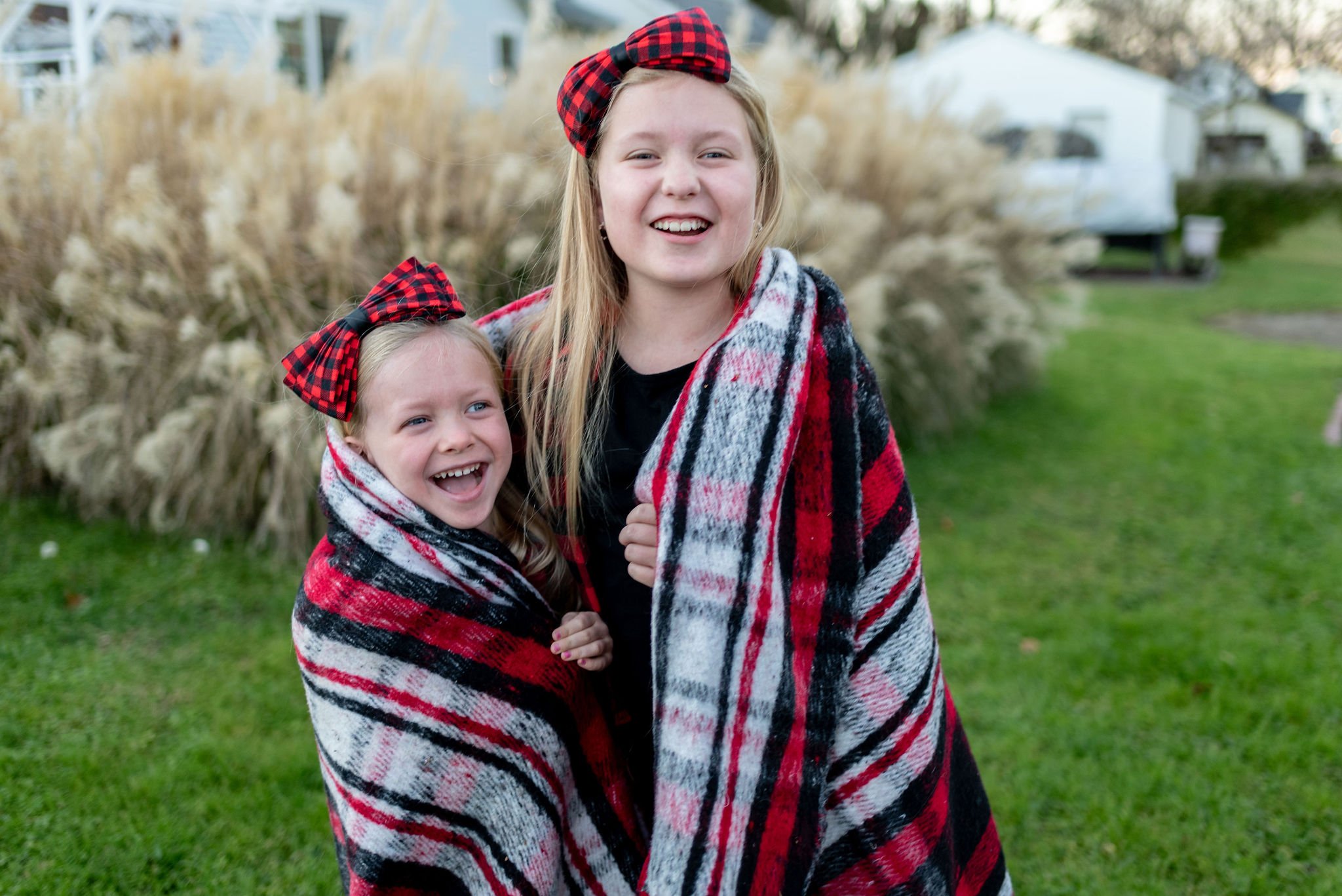 Sister’s bundled together in a blanket outside for holiday family photo