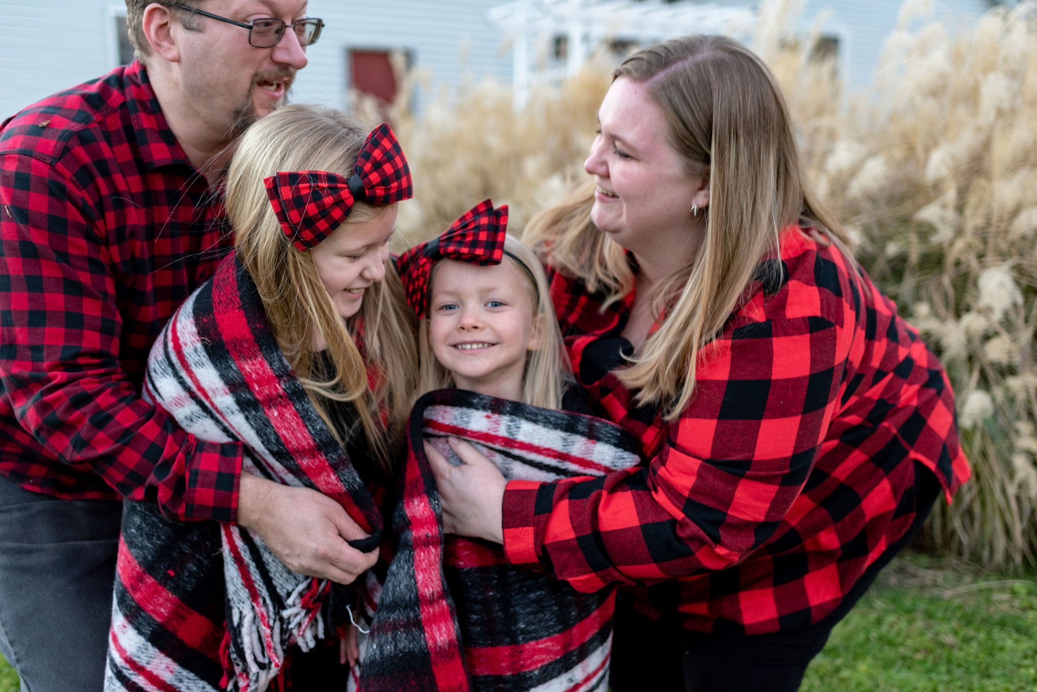 Mom, dad and kids together for holiday family photo, outside, with a blanket around the kids