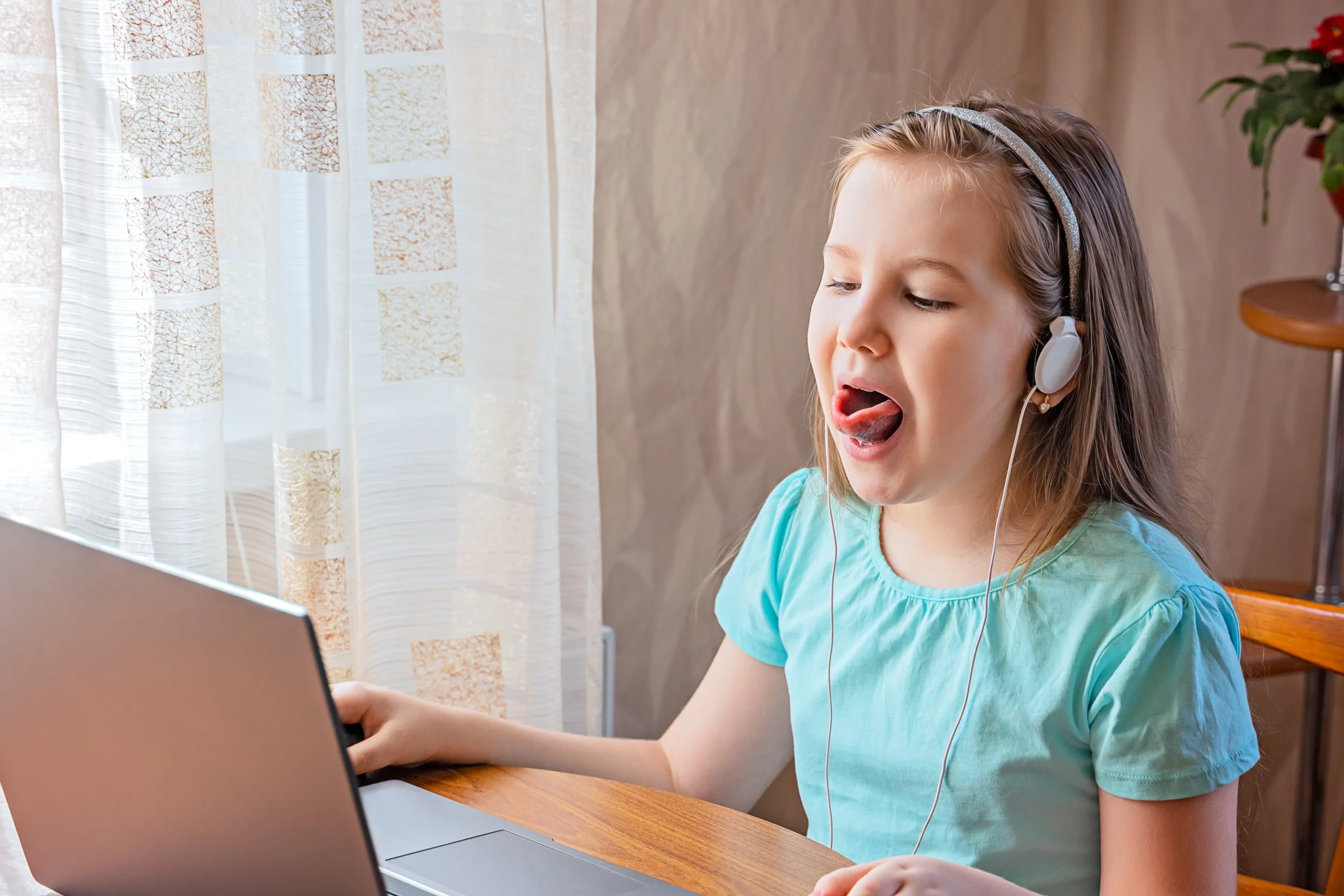 Child practicing speech sounds during an online speech therapy session while learning correct tongue placement.