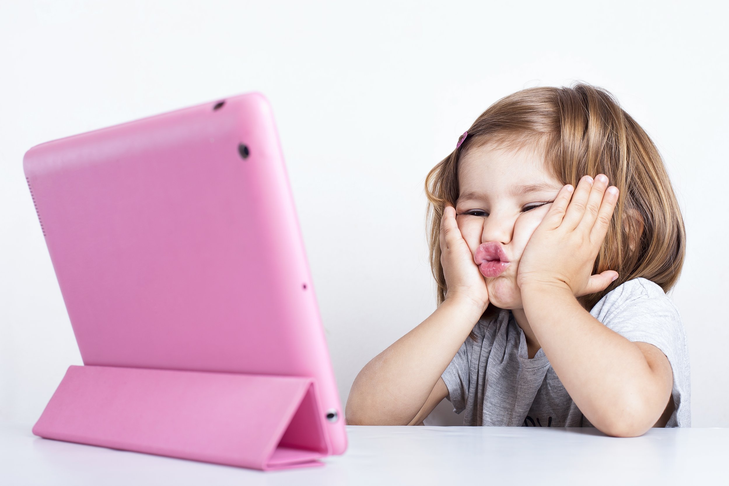 Child participating in online speech therapy for phonological disorders using a tablet during a virtual session at home.