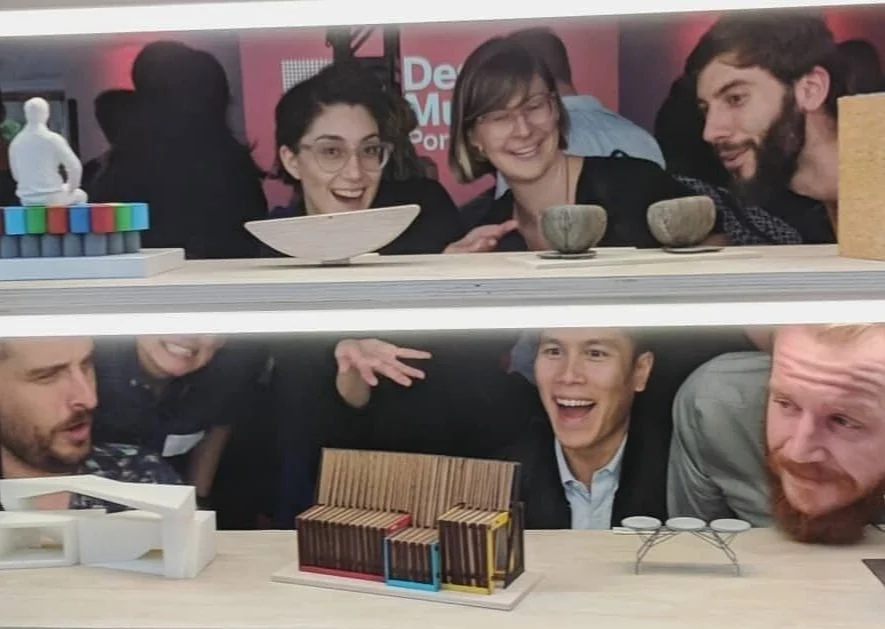 The design team goofs around behind a small model of the flexible +Bench.