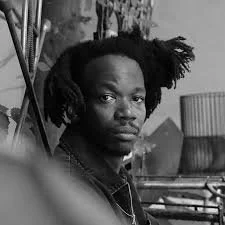 Black and white photo of a person with natural hair looking at the camera.