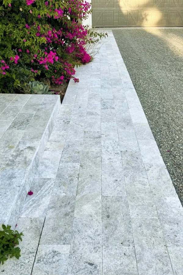 Stone paver pathway and step made from silver-greige travertine pavers, with fuchsia bougainvillea in the background