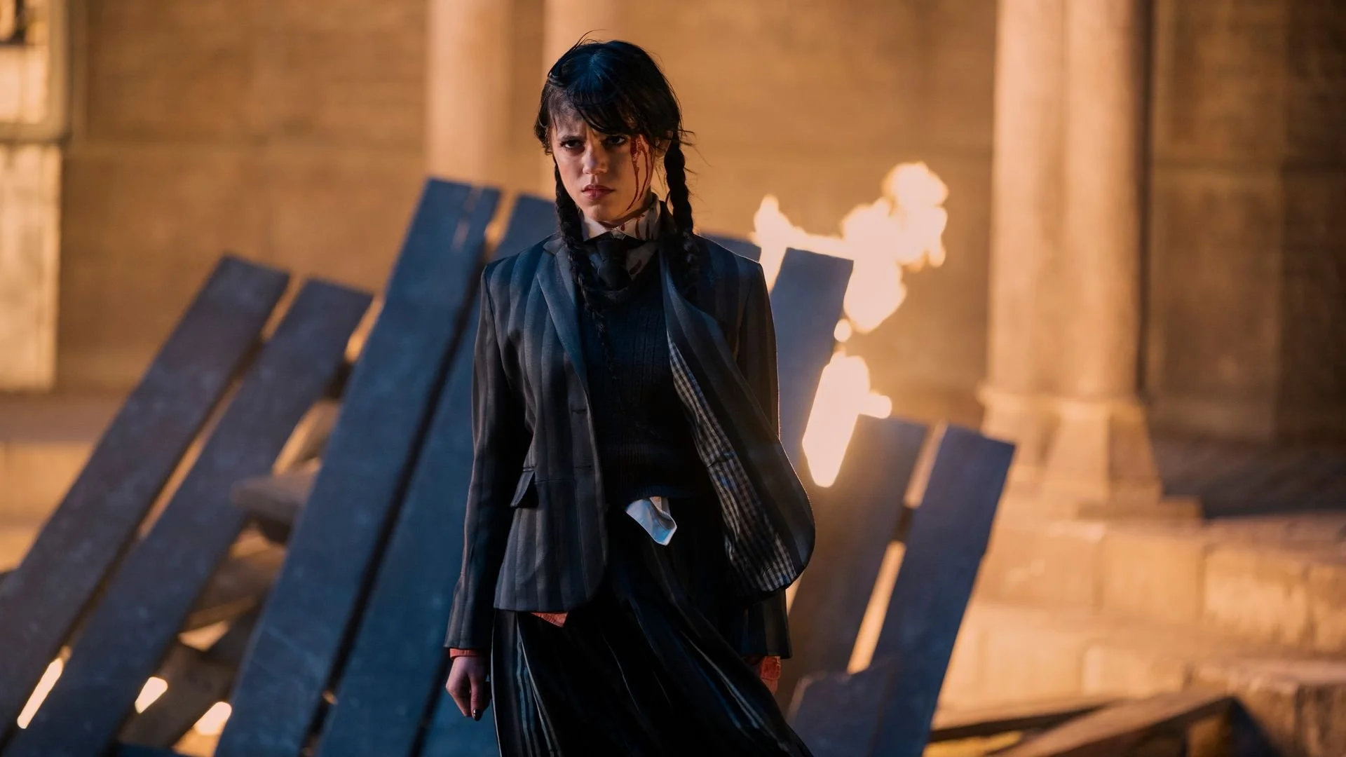 Person standing dramatically in front of burning debris