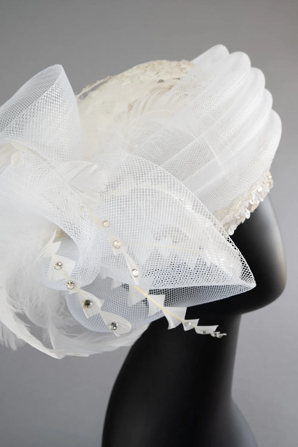 Cloche covered in white scalloped sequin braid with white crinoline, feathers and rhinestones