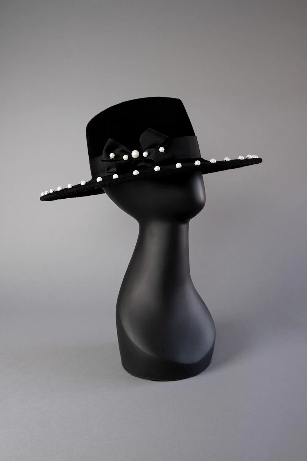 Black velour fedora wide brim edged with 4mm pearls. Black grosgrain band and bow with matching pearls.