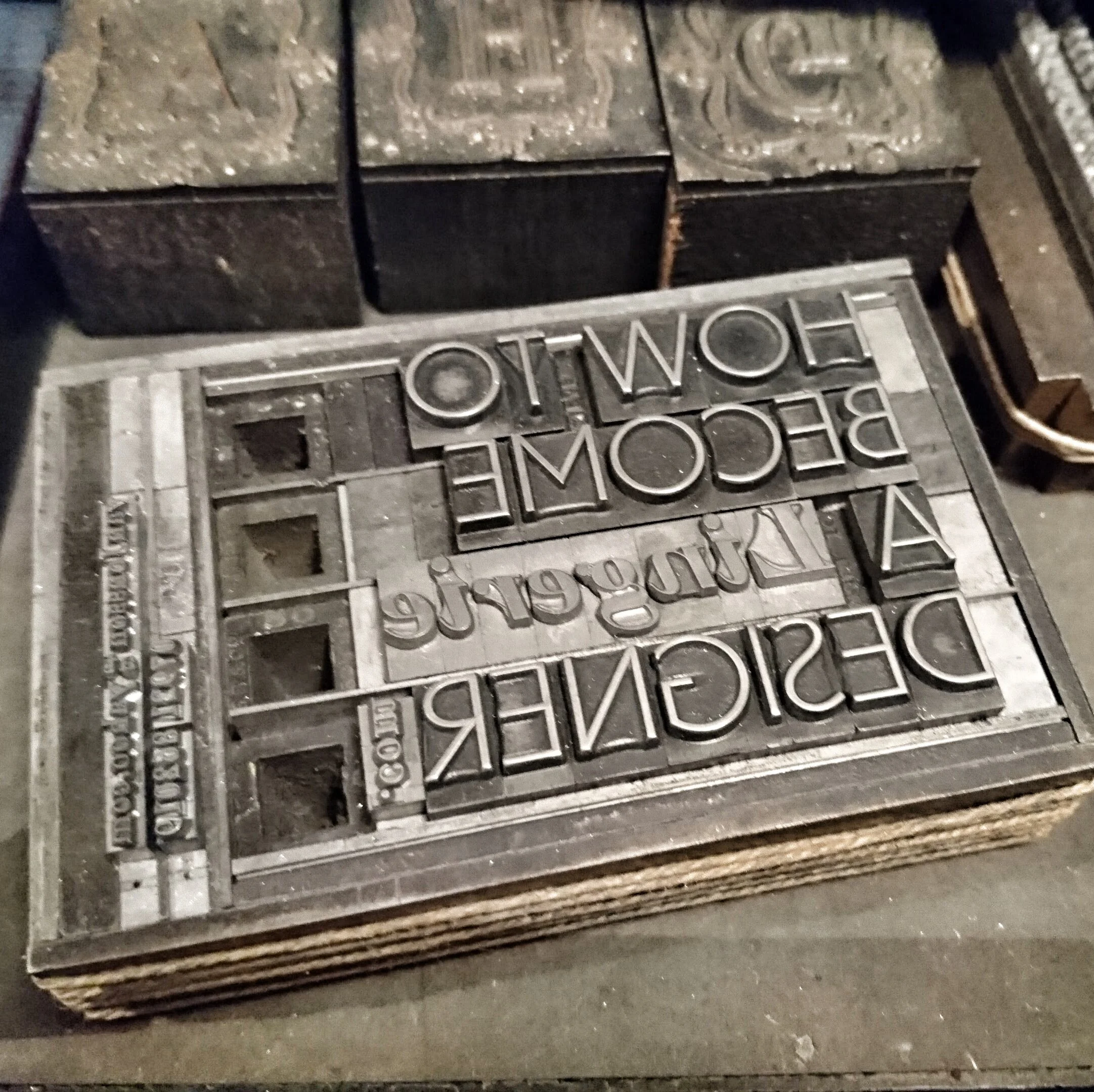 Stack of vintage metal letterpress printing blocks with reversed text for printing.