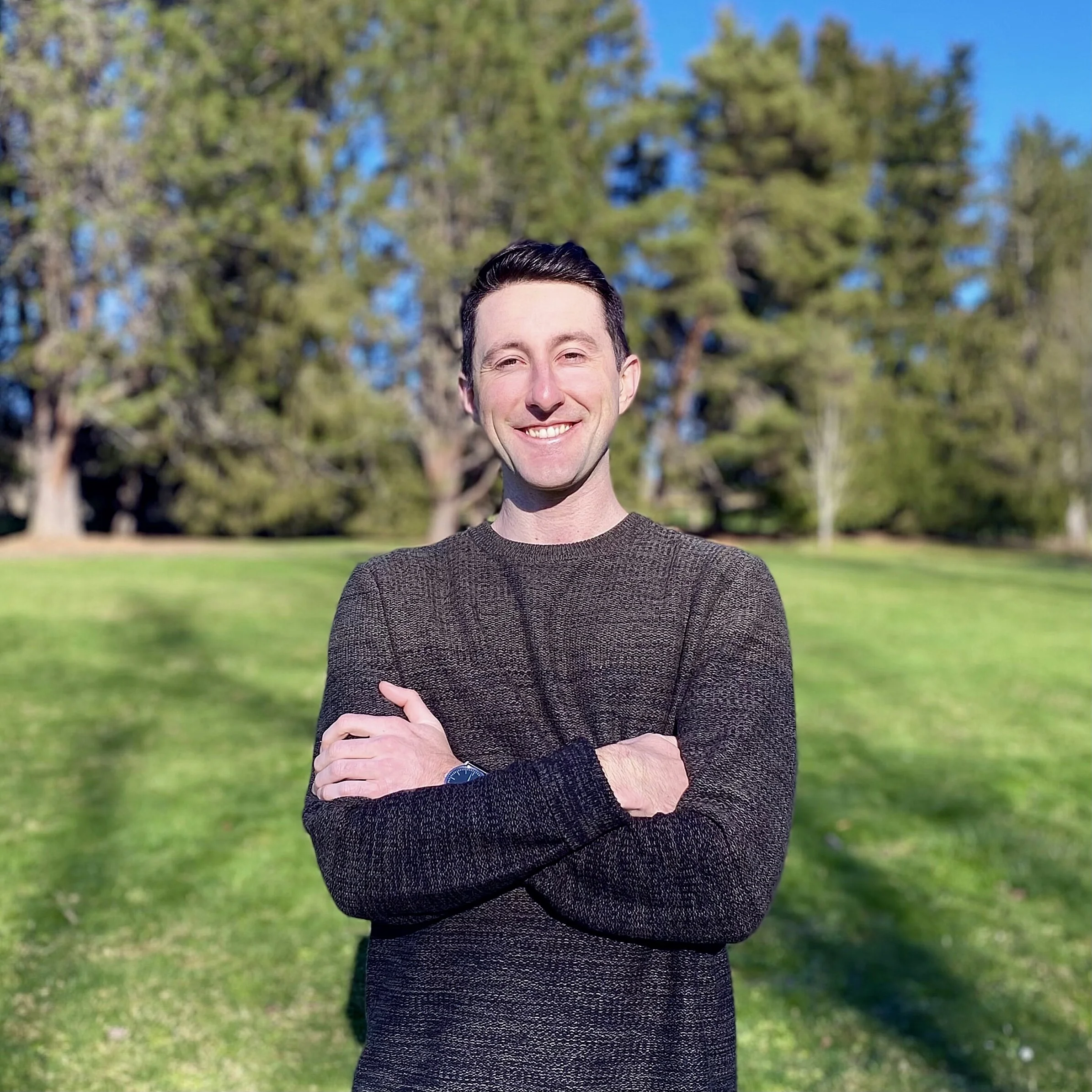 the owner of DL Viz standing in a park while smiling and the sun attacks his eyes.