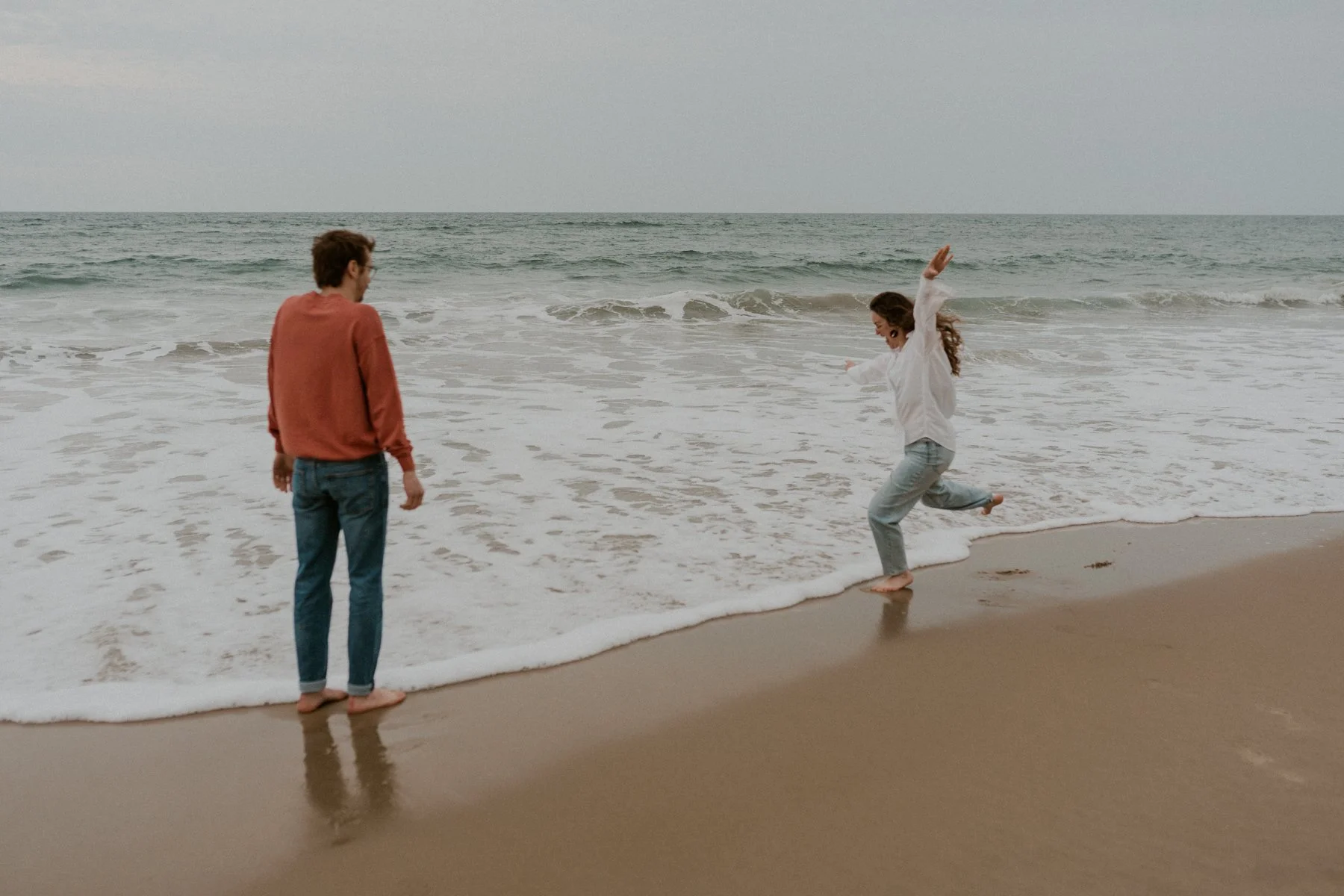playful couple running on beach OBX engagement session