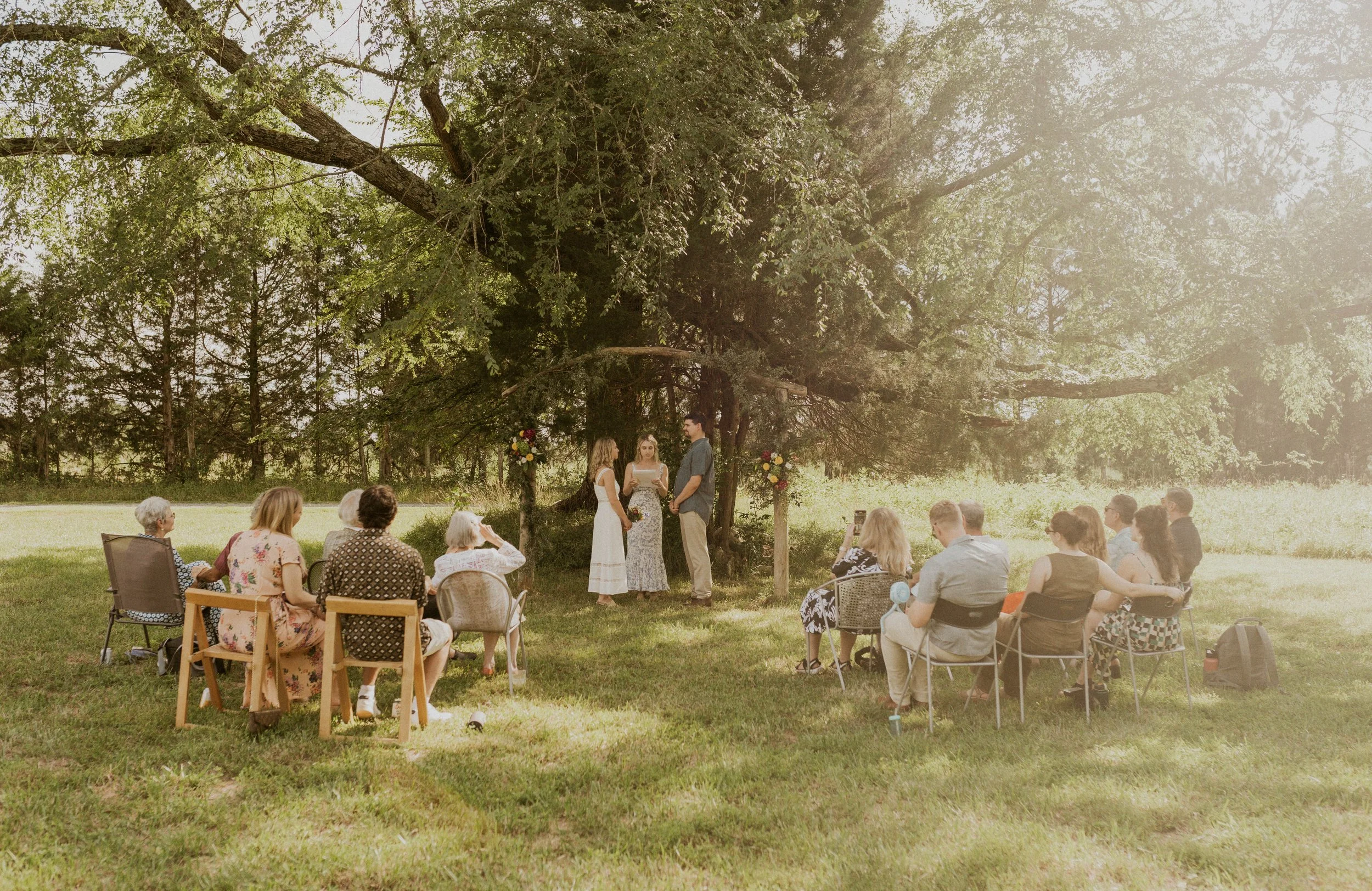 Couple exchanging vows beneath a large tree during an intimate family land elopement