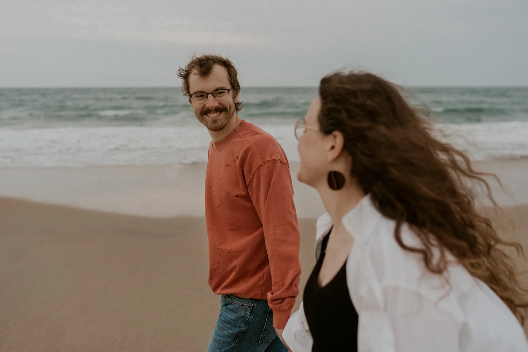 couple walking along foggy beach Outer Banks engagement session