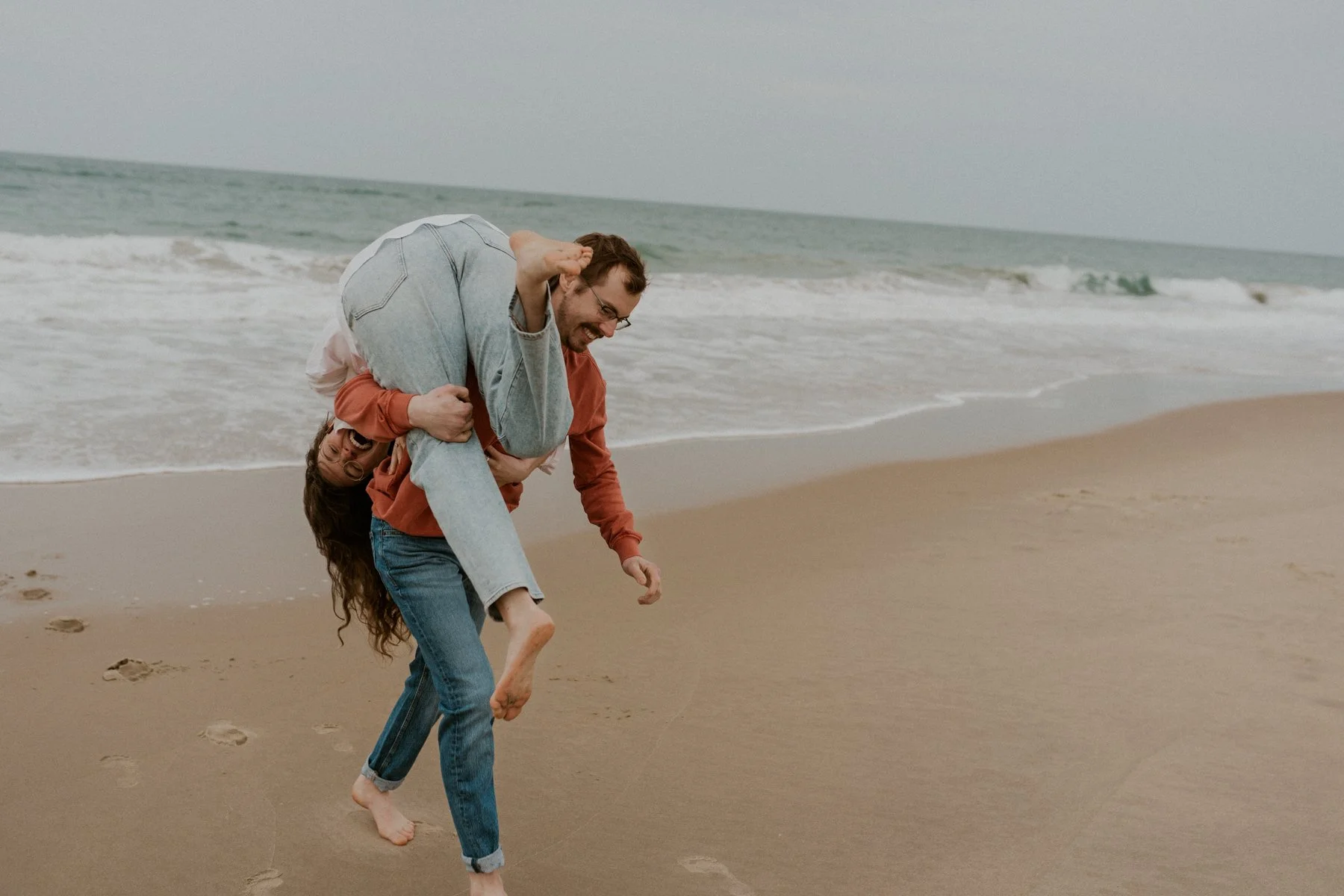 playful couple running on beach OBX engagement session