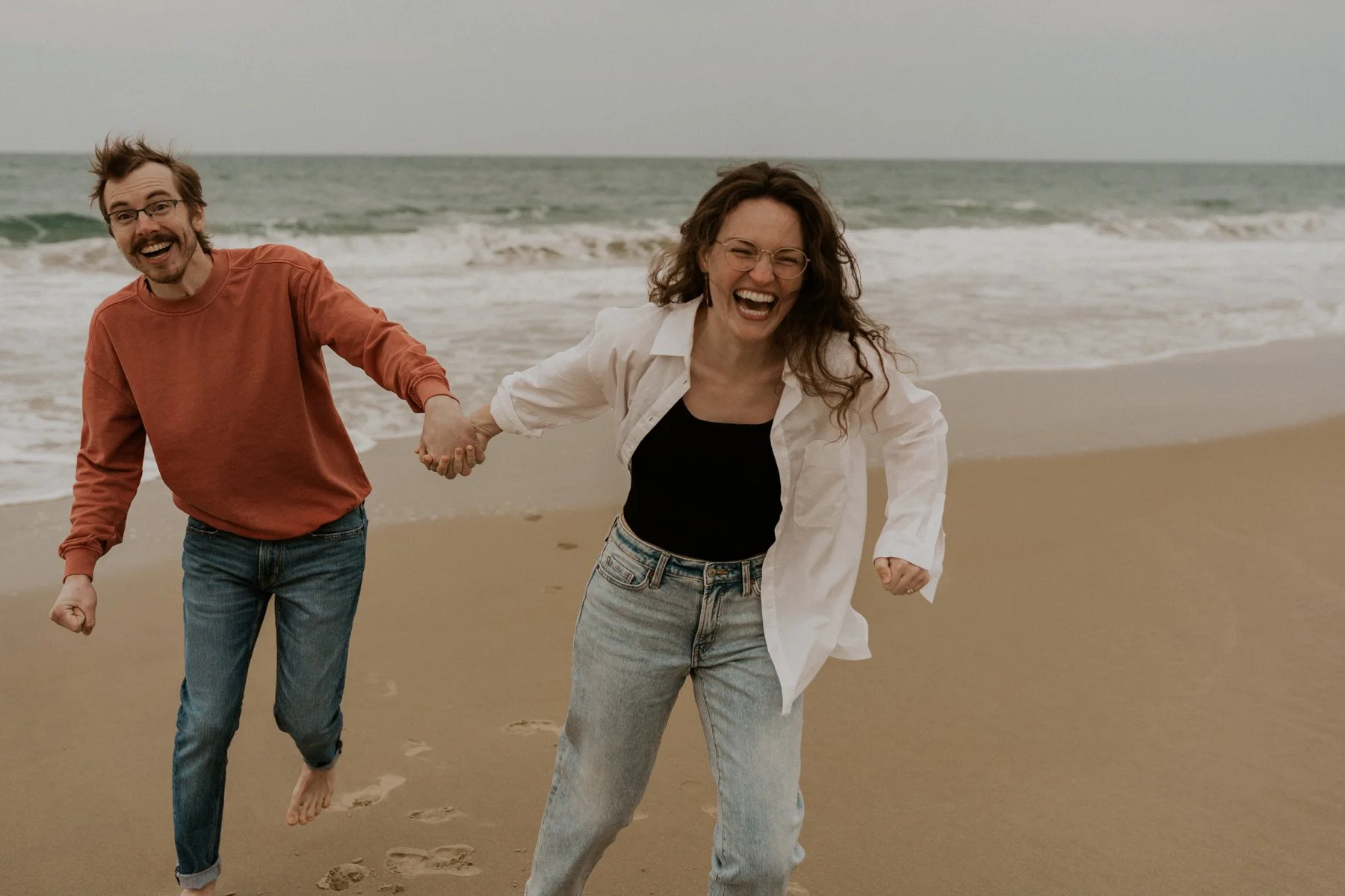 playful couple running on beach OBX engagement session