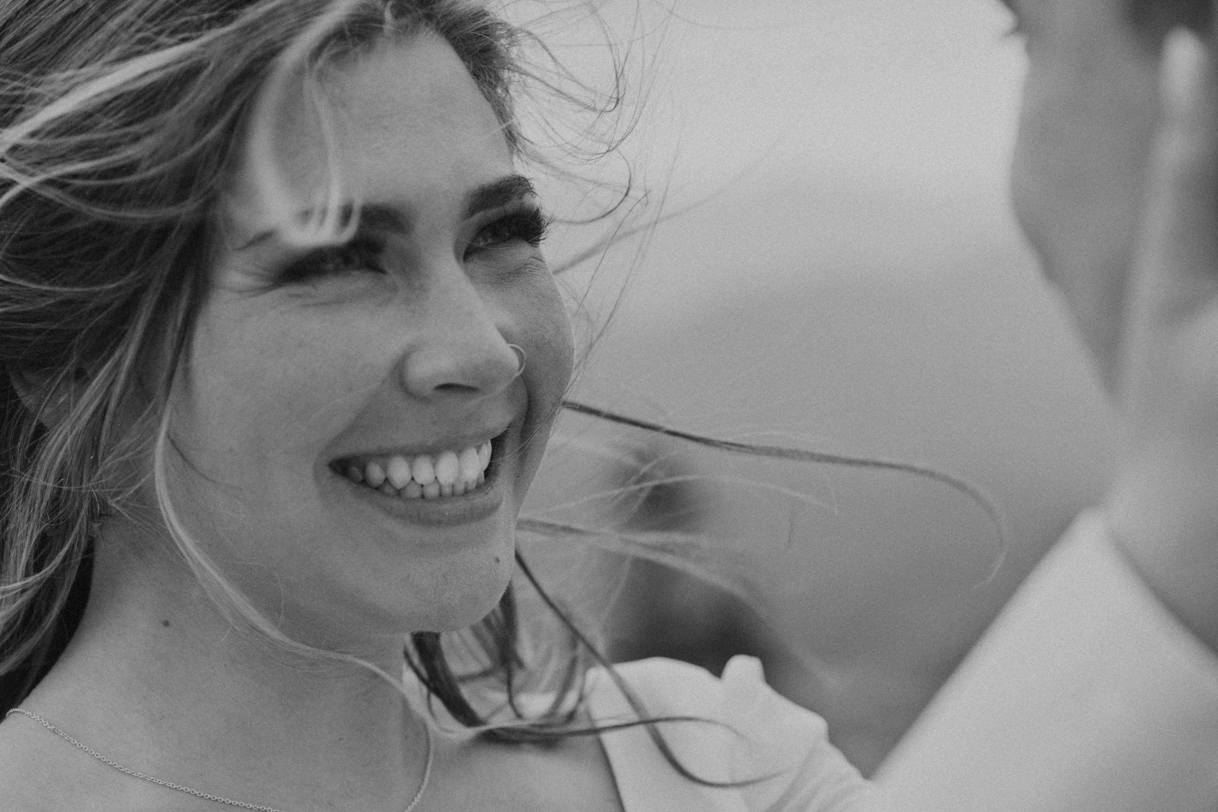 Bride embracing groom with windblown hair in her face, emotional candid moment in Denmark