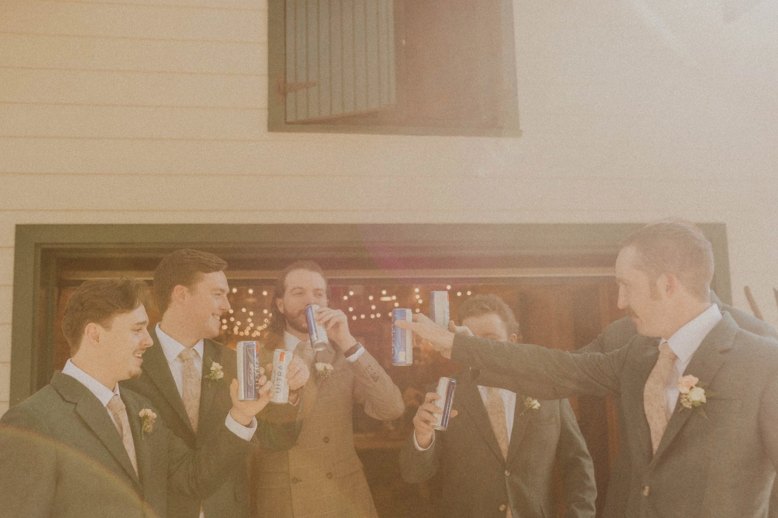 Groom sharing beers and laughter with groomsmen before ceremony in Raleigh