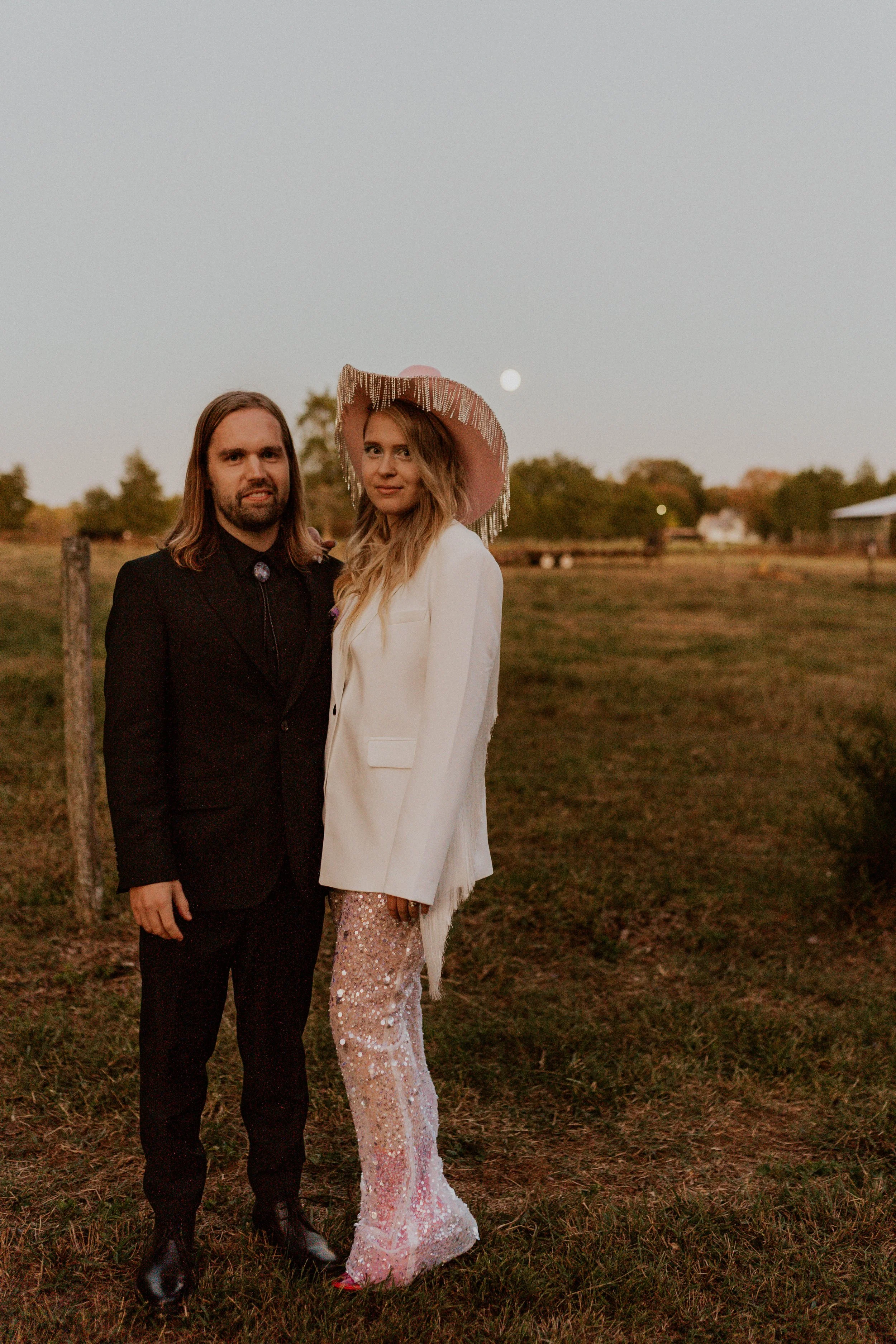 Sol wearing sparkly pants, a white fringe jacket, and a pink cowboy hat at her Space Cowboy Disco wedding reception