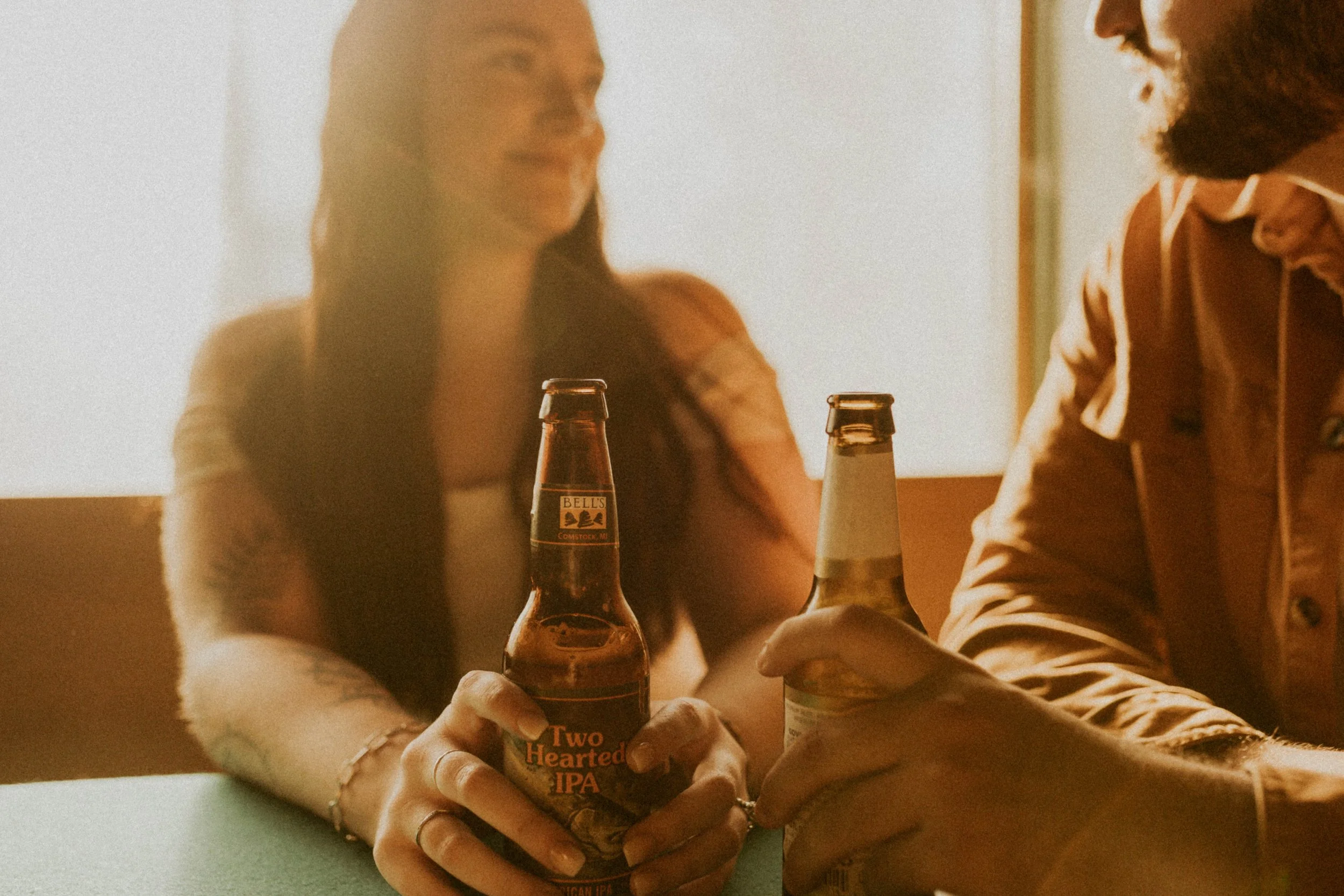 Couple laughing together over beers during Durham engagement photos