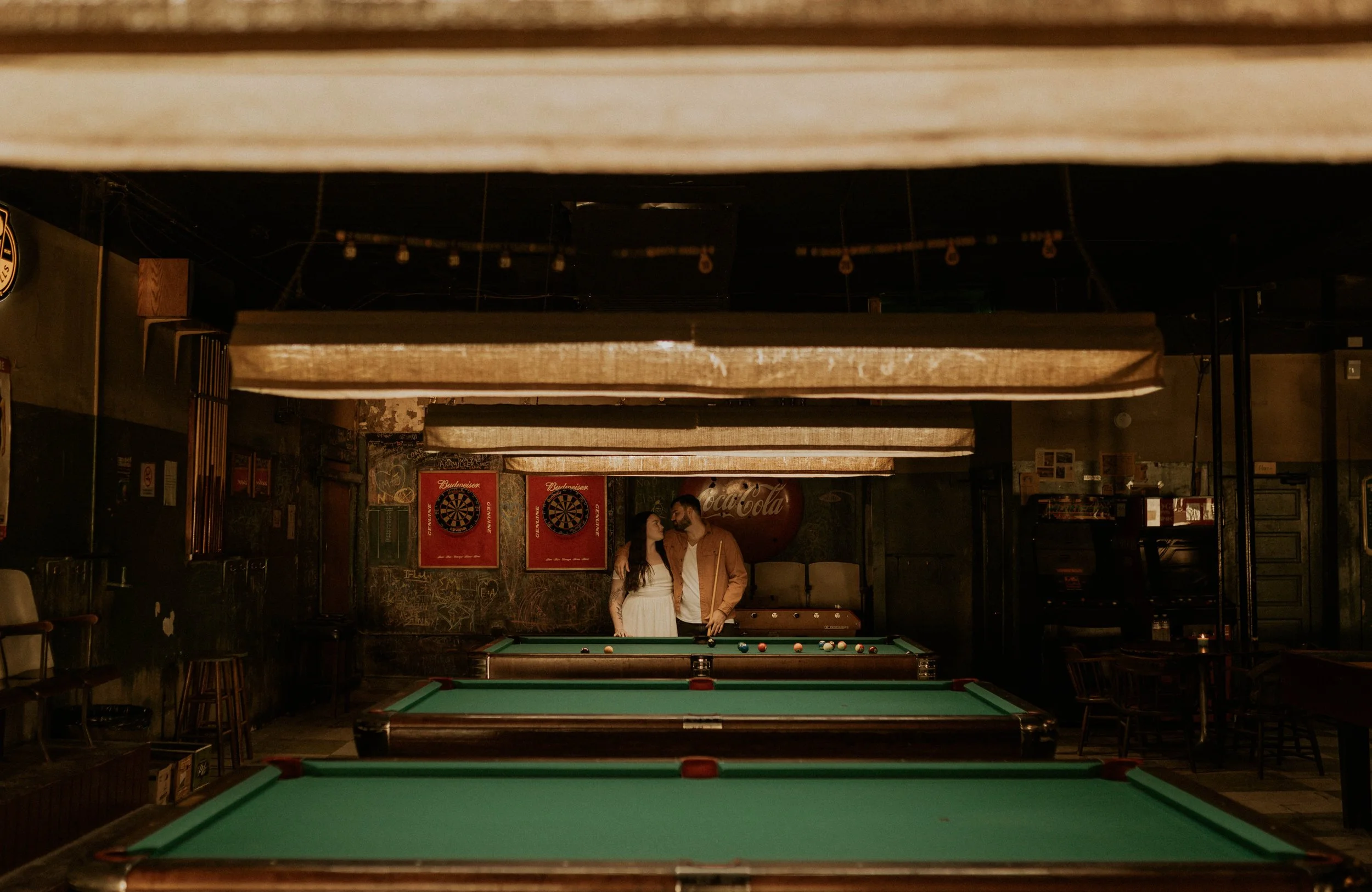 Couple playing pool during Durham engagement session at local date spot