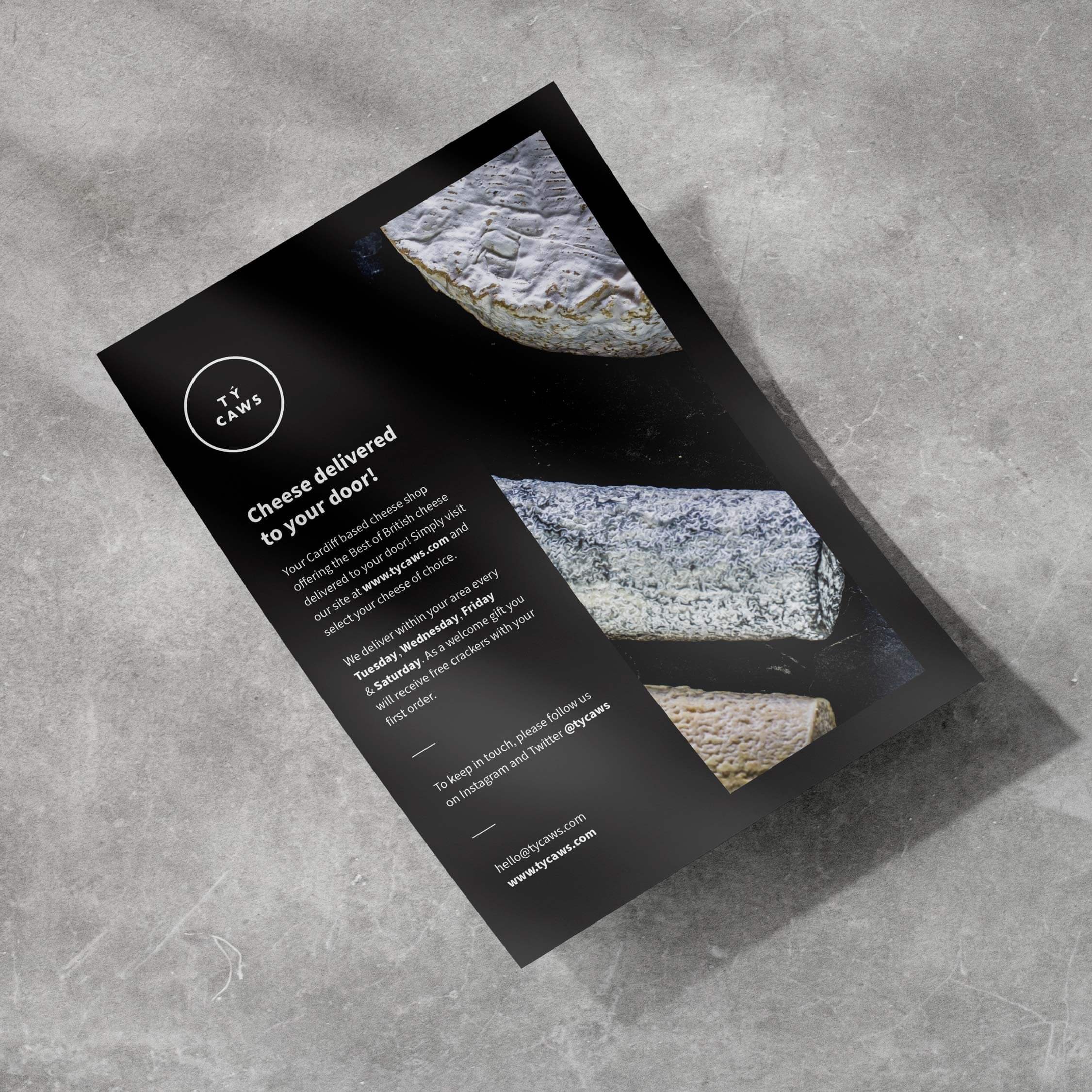 A partially opened black box of cheese with Italian words on it, placed on a gray textured surface.