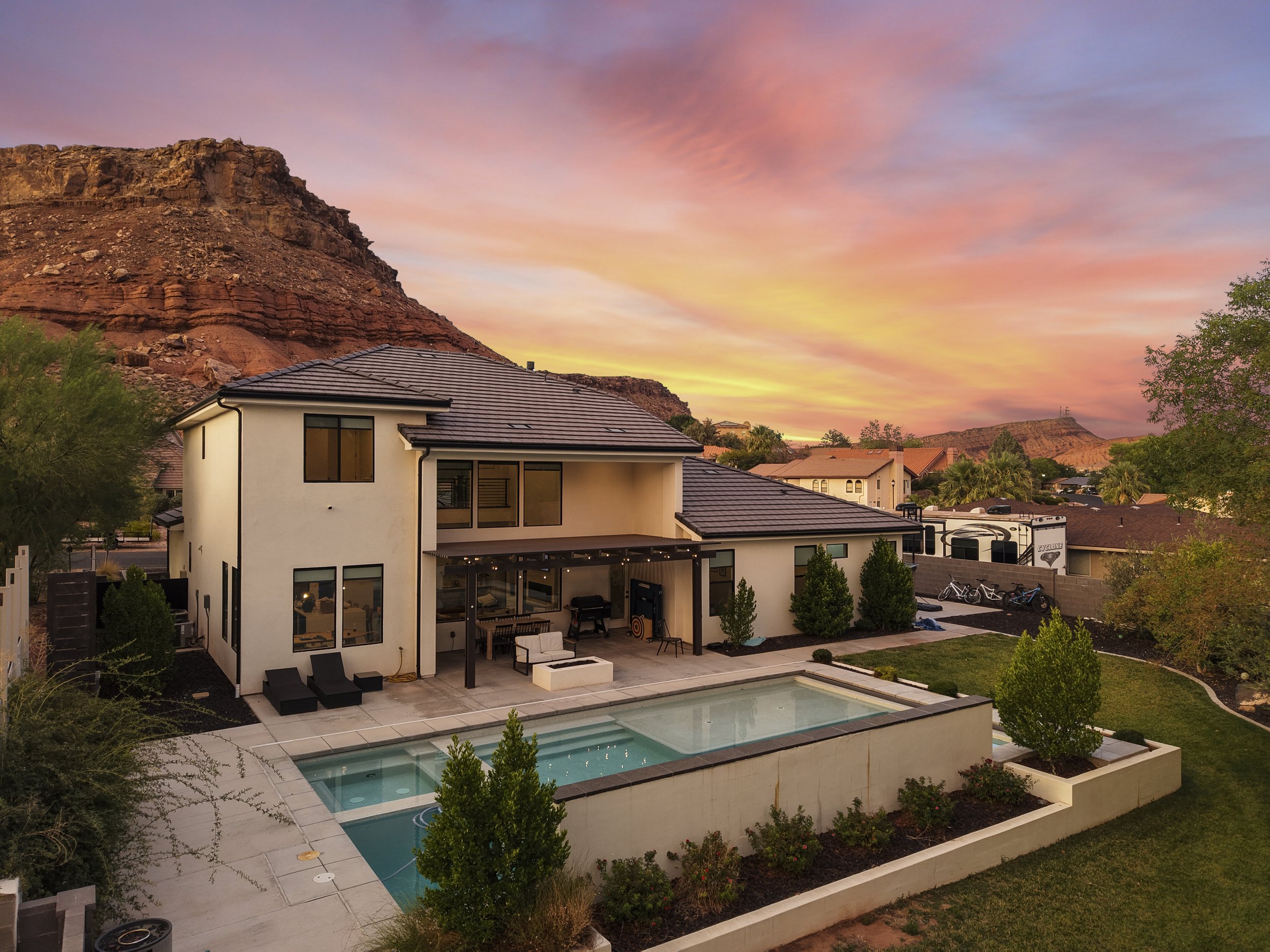 Aerial image of St George home with pool backed up against red rock cliffs - Real estate photography