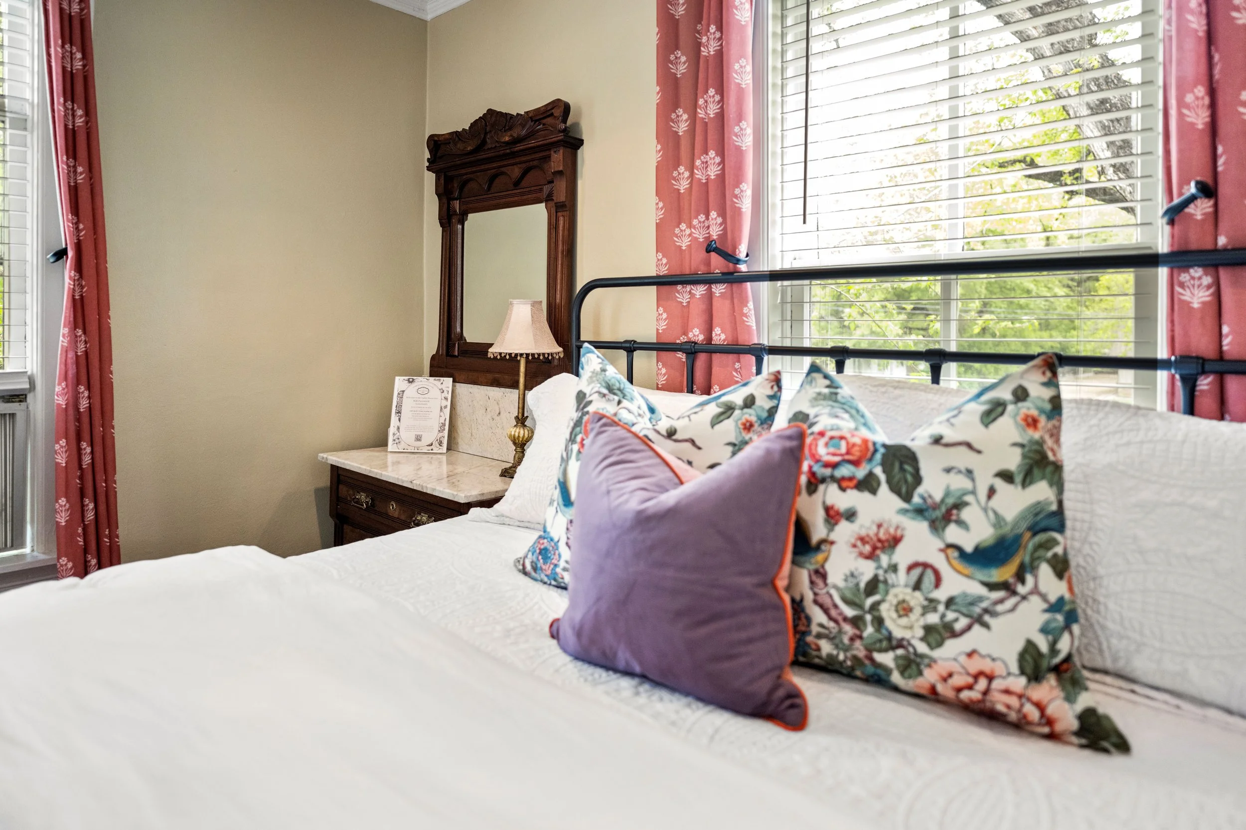 floral throw pillows on a queen size wrought iron bed