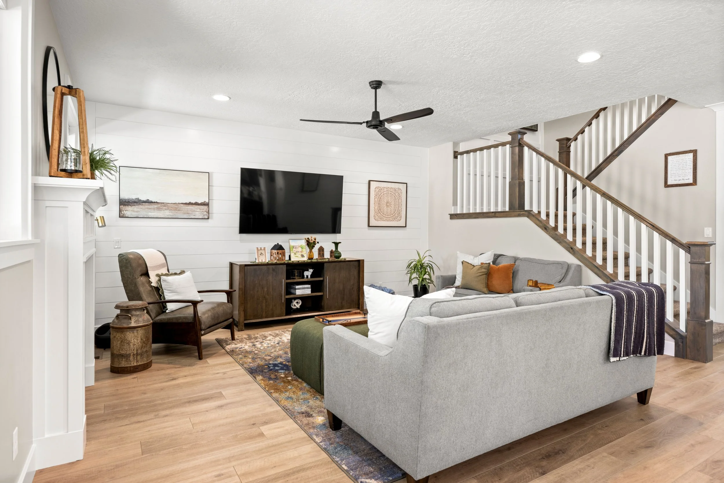 Living room with shiplap walls, fireplace and view of staircase to second level