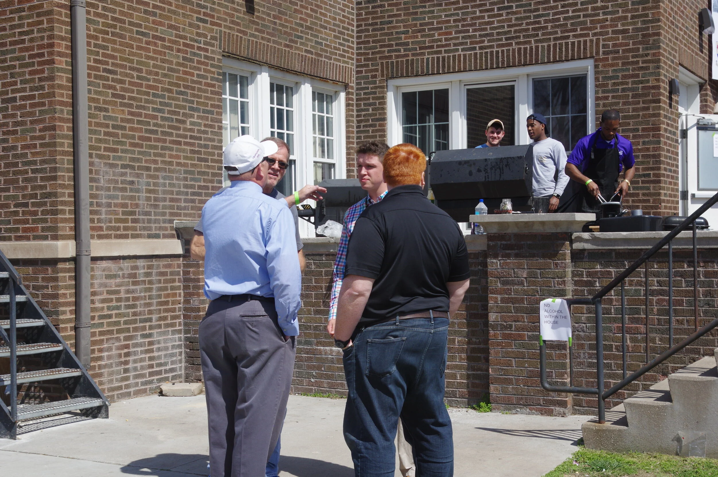 Cooks on the veranda, members talk in foreground.JPG
